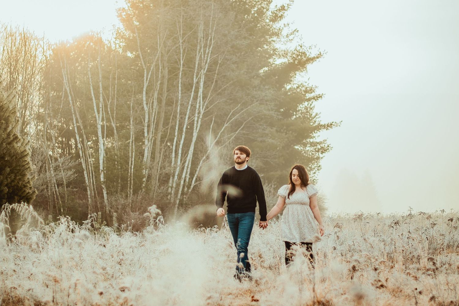 Family walks through a snowy winter forest path with tall birch trees and white ground cover.