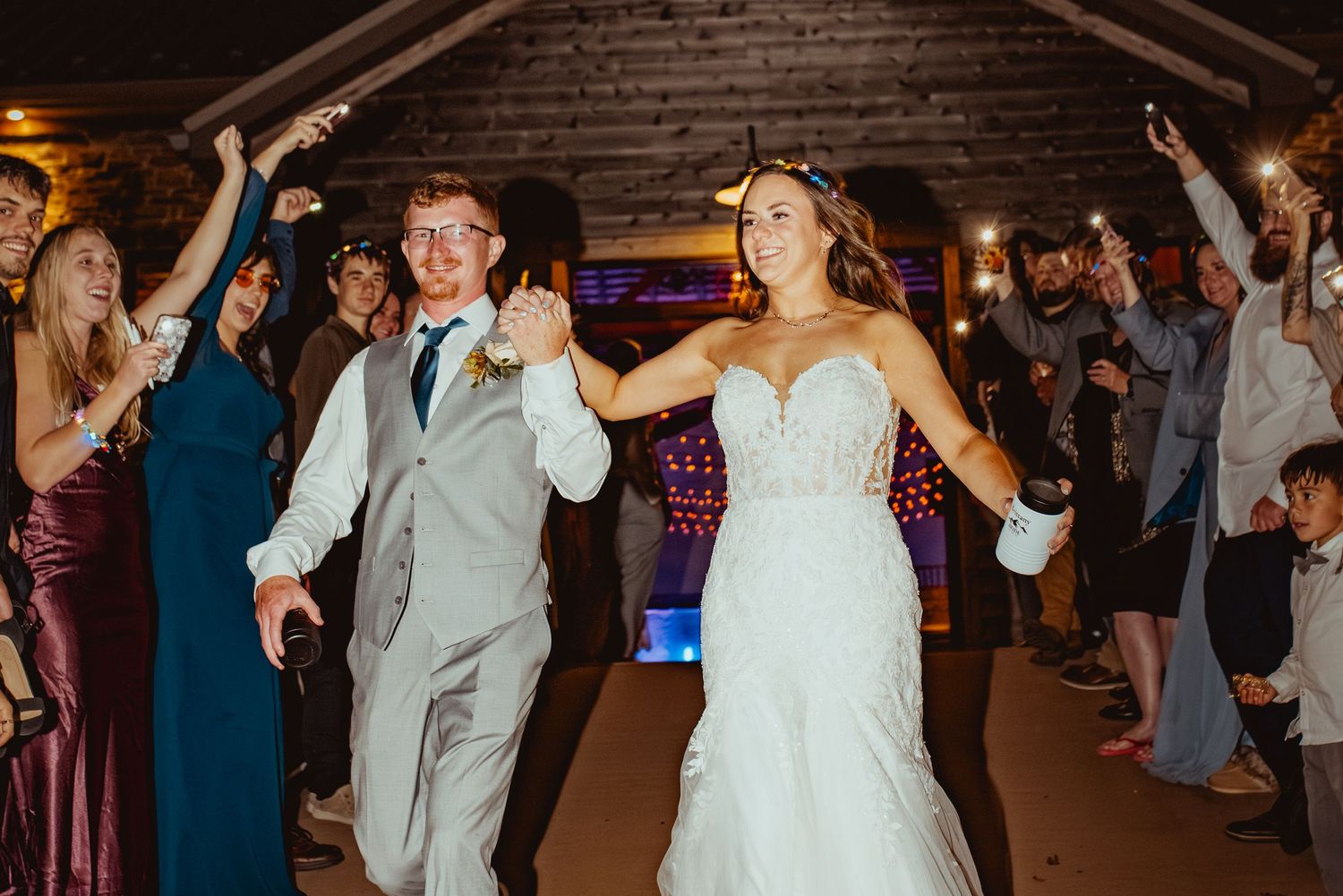 Wedding reception dance floor filled with guests celebrating under ambient lighting.