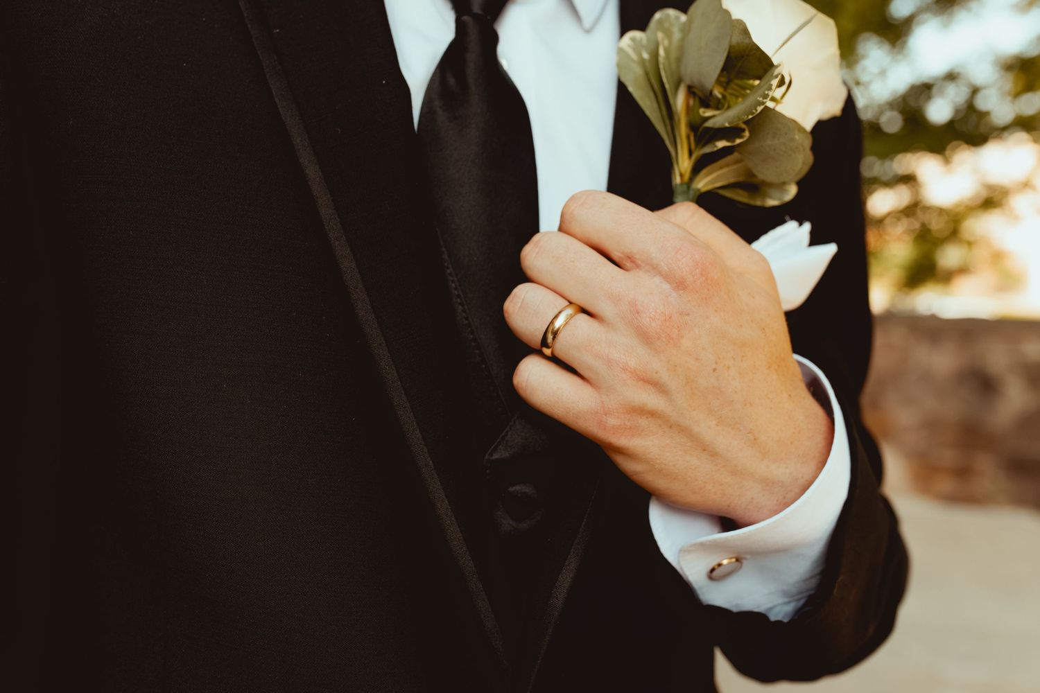 A couple holds hands while wearing formal wedding attire during a golden sunset ceremony.