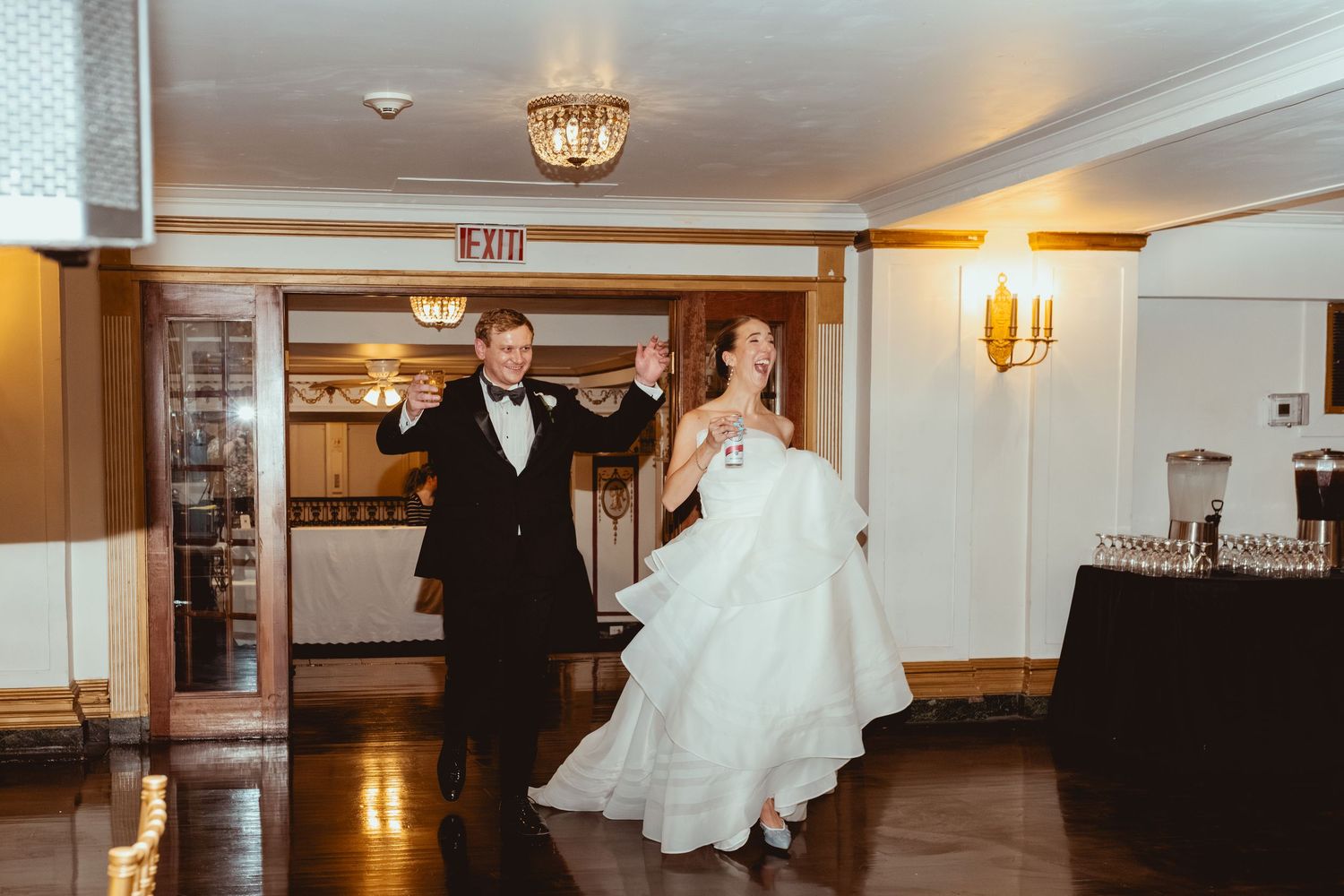 Couple walking through an elegant hallway with dramatic lighting and classic decor.