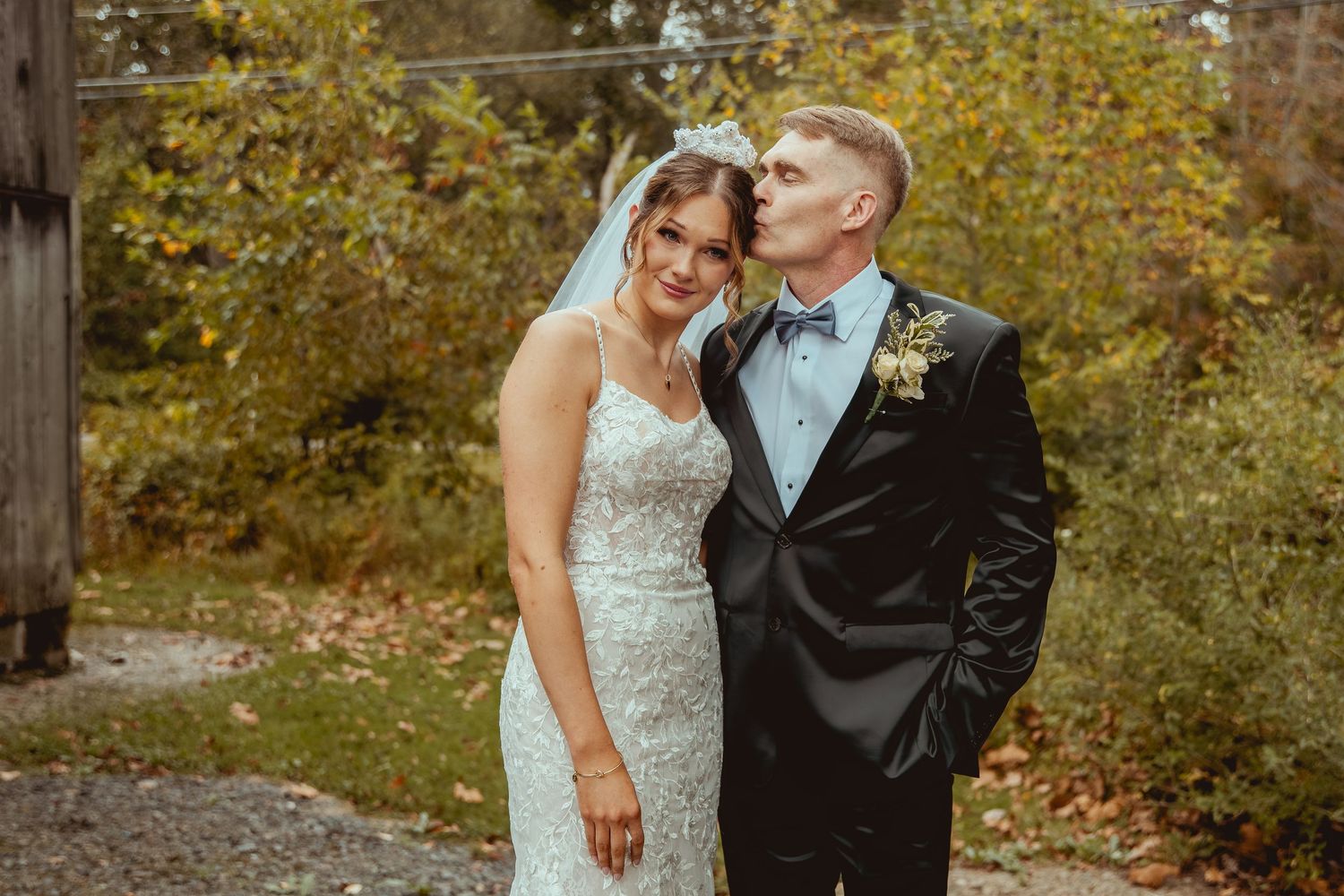 A couple shares a tender moment in an autumn outdoor setting.
