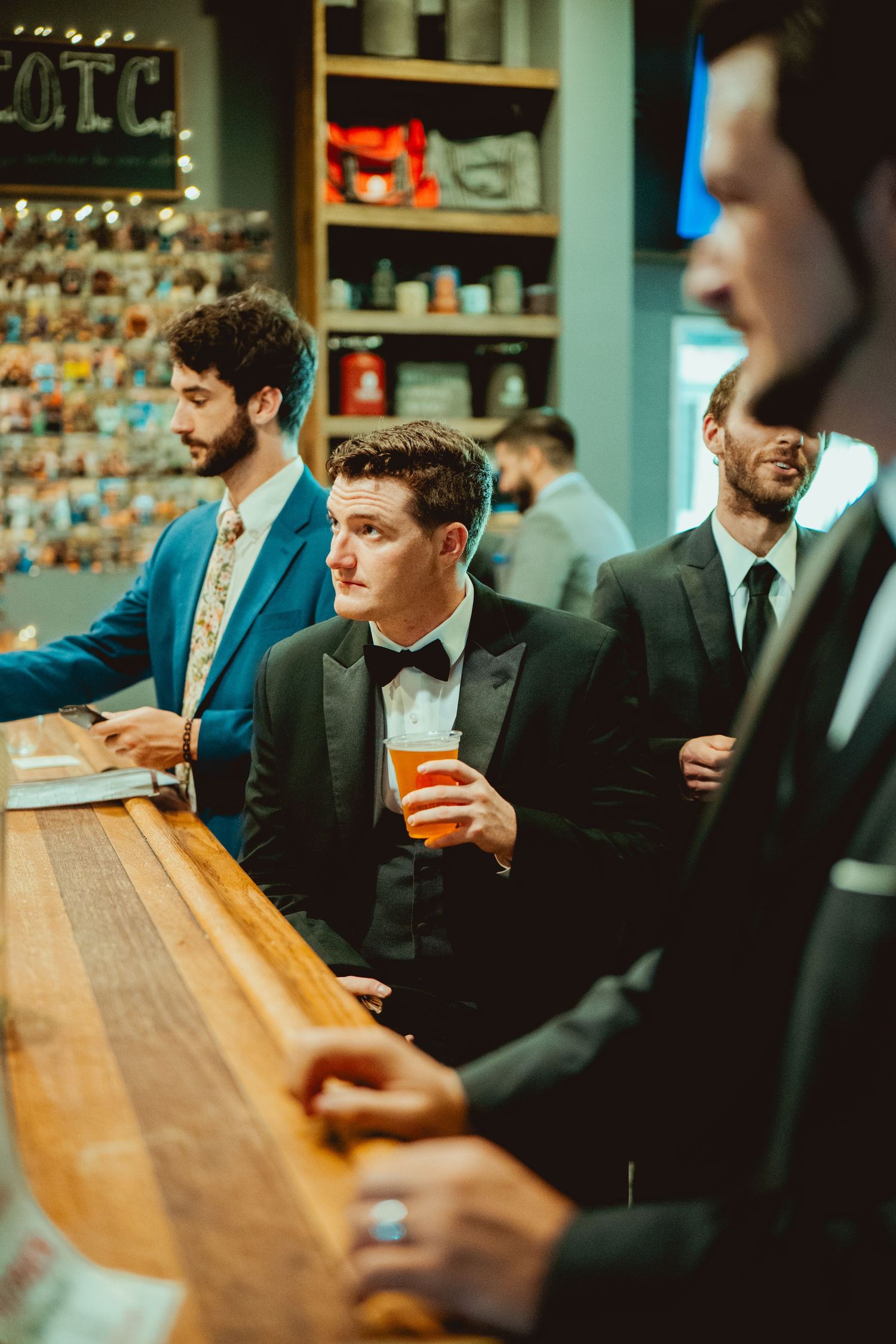 Groomsmen in dark suits gathered at a wooden bar counter.