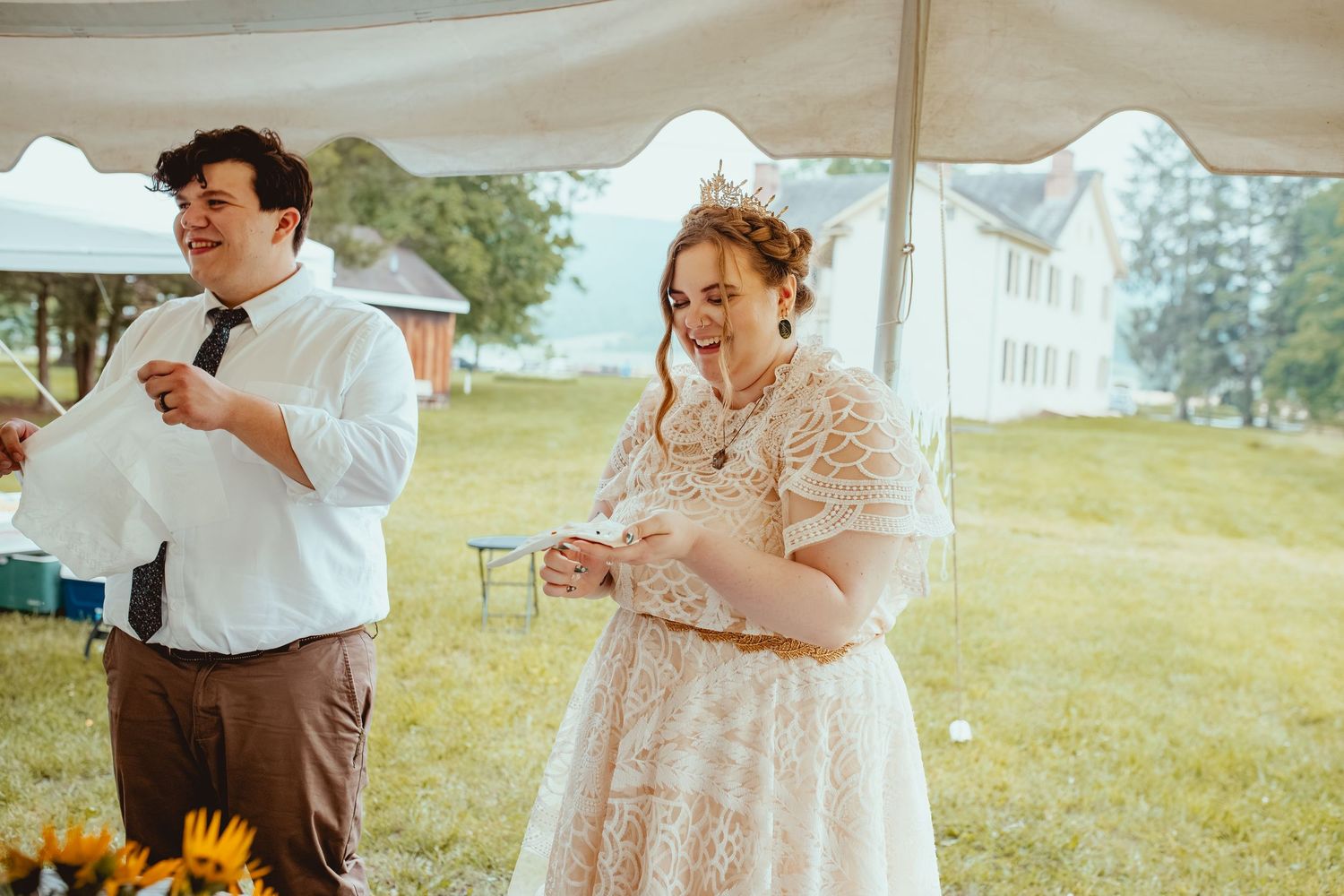 A couple shares an intimate moment during their outdoor wedding ceremony in a sunlit field.
