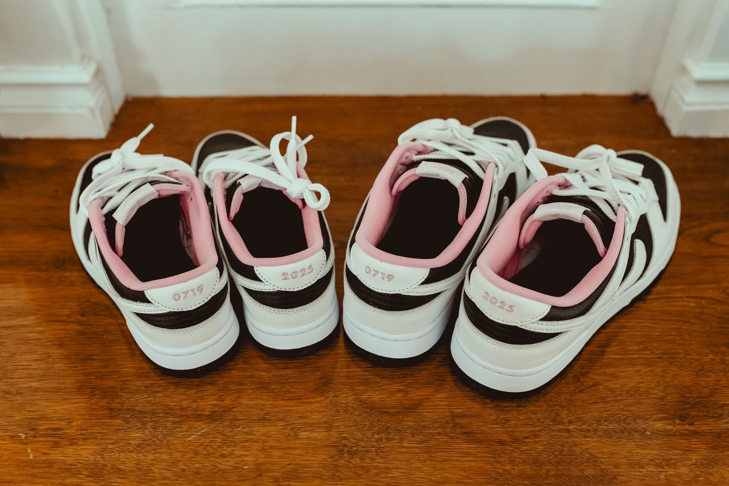 Several pairs of white sneakers arranged in a row on a wooden surface.