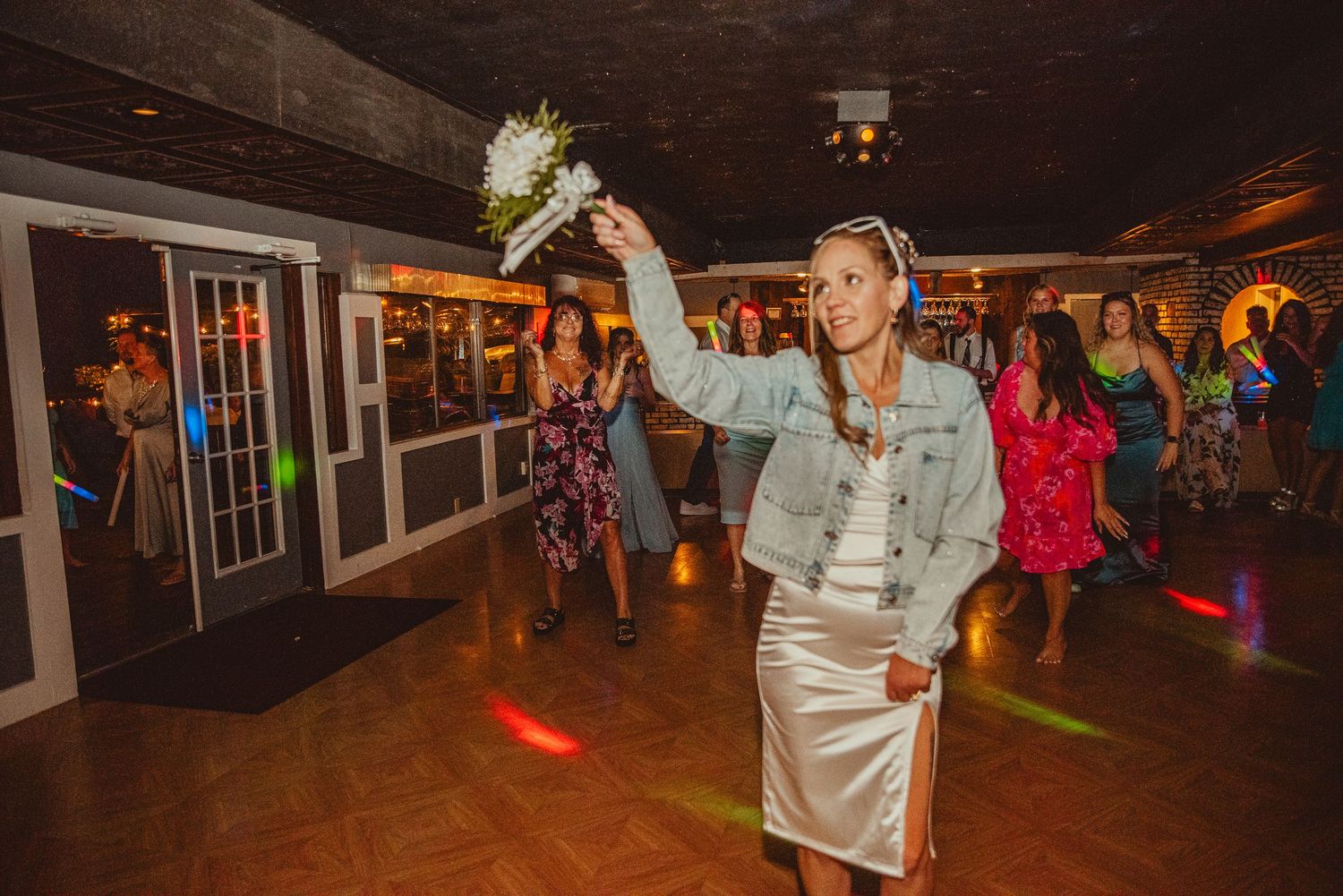 Wedding reception dance party with guests celebrating on a dimly lit dance floor.