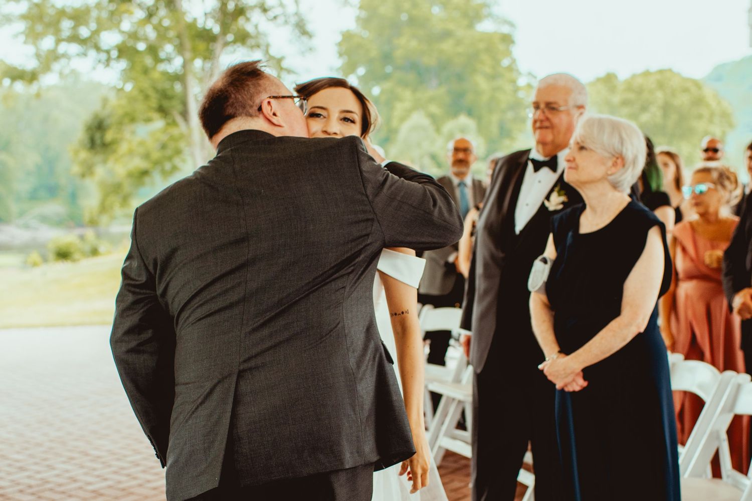 Emotional ceremony moment captured during outdoor wedding with guests looking on.