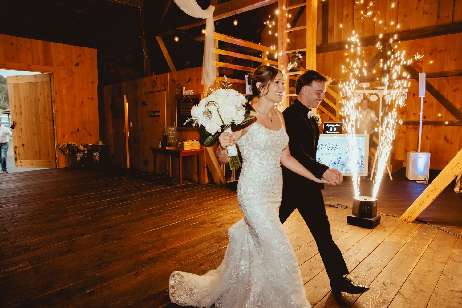Couple dancing in rustic barn venue illuminated by warm string lights.
