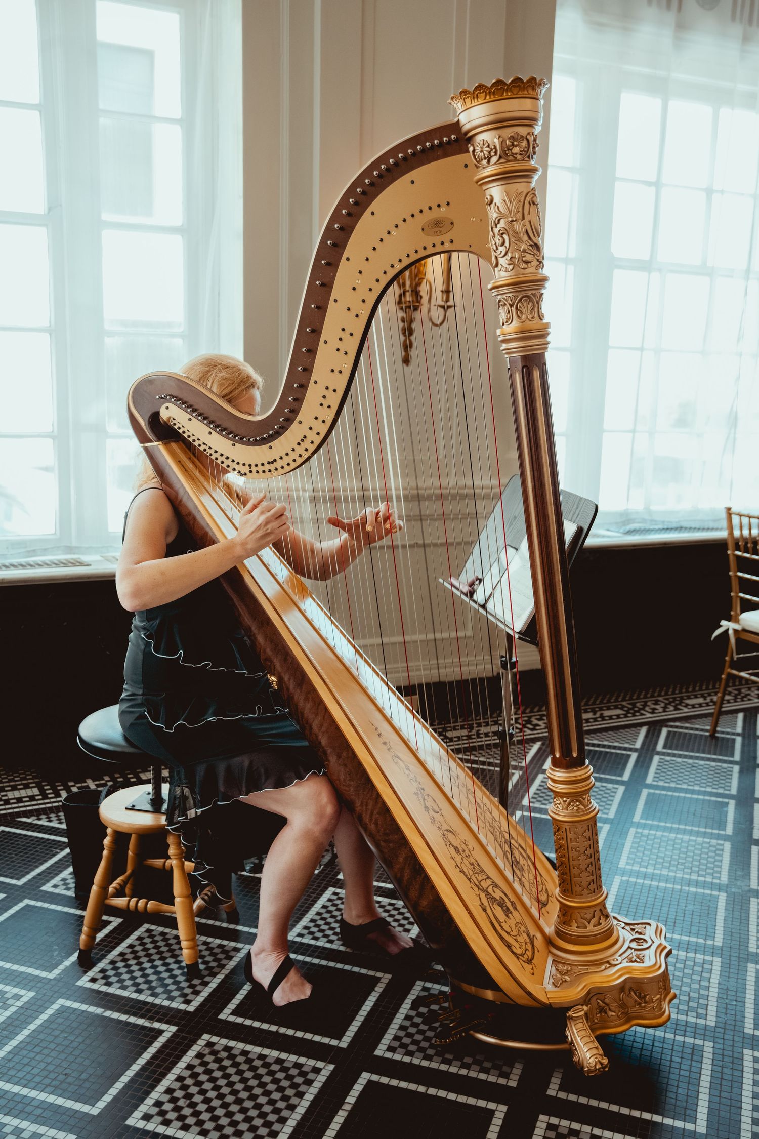 Elegant golden harp being played in a room with geometric patterned flooring.