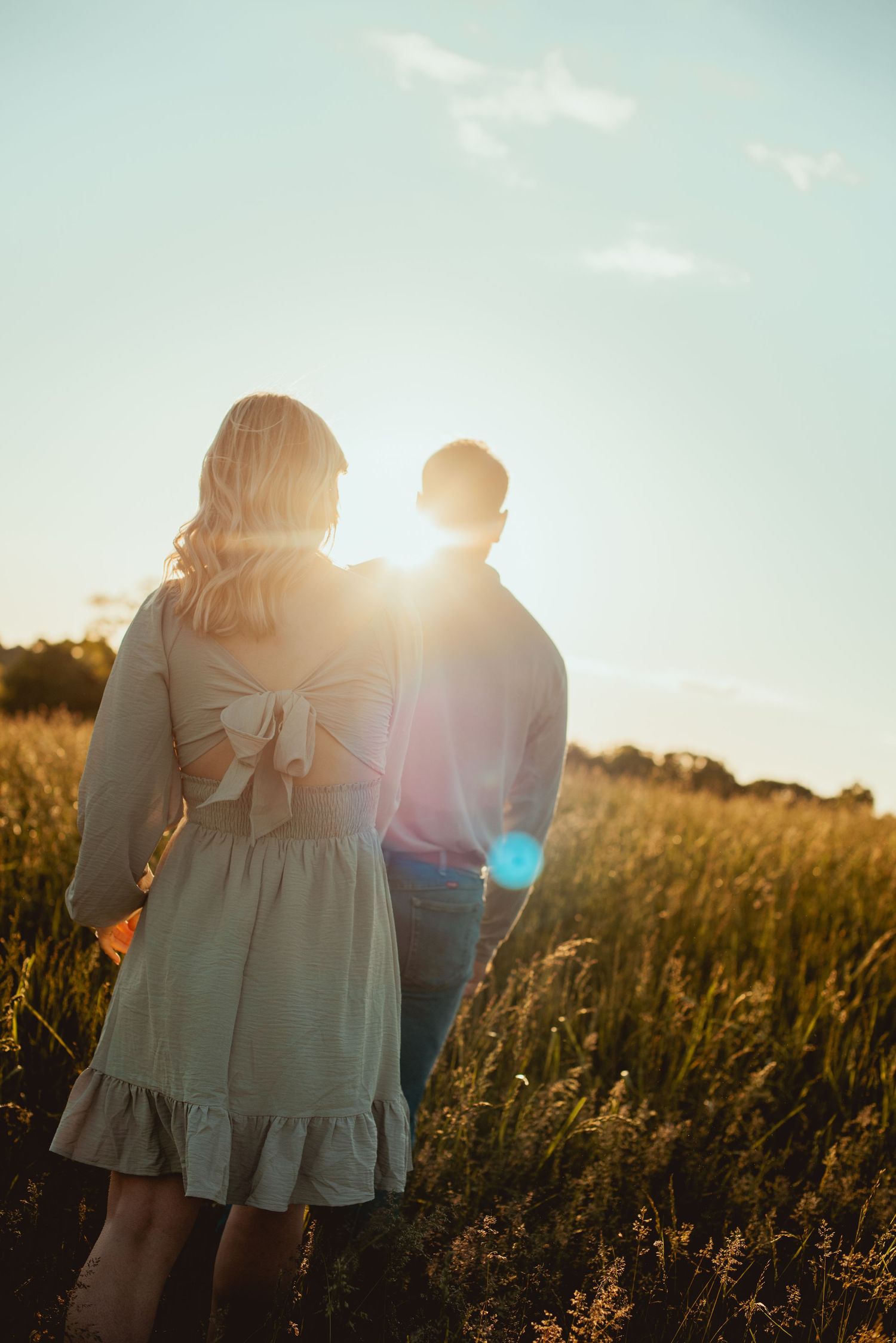 A backlit group embraces in a golden field at sunset creating a dreamy silhouette against the sky.