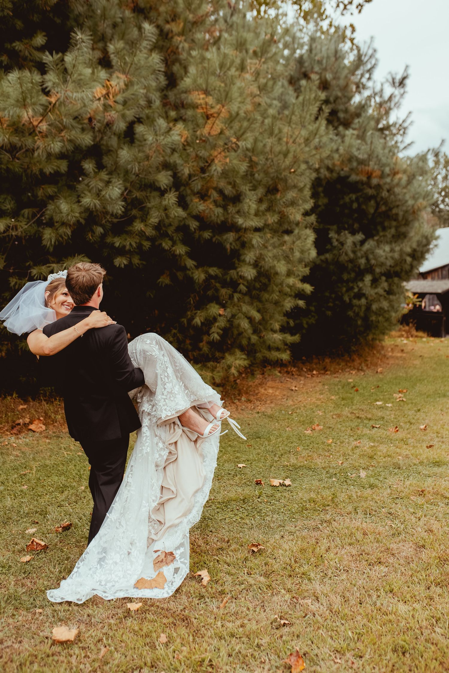 Wedding couple performing playful dance moves on grass during fall photo session.