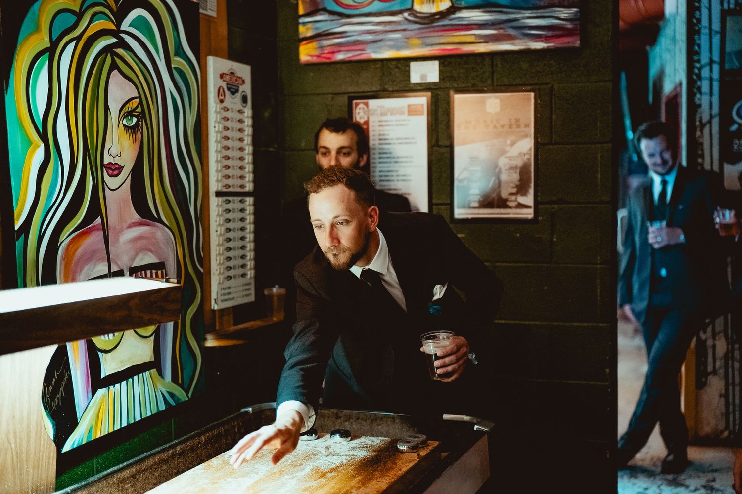 Guests mingling and socializing at an indoor event with colorful wall art in the background.