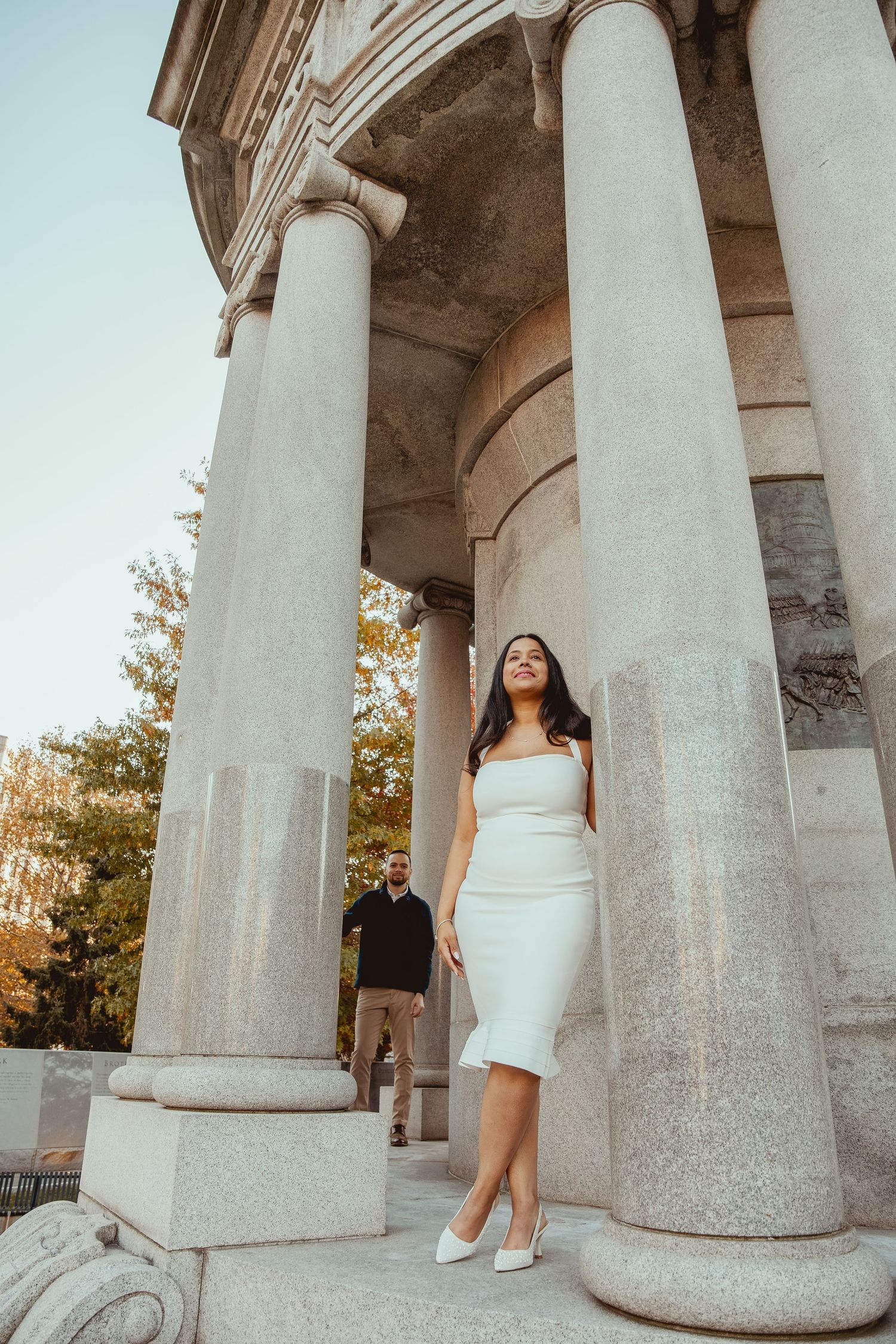 A person in a white dress poses elegantly between classical stone columns in a series of artistic photographs.