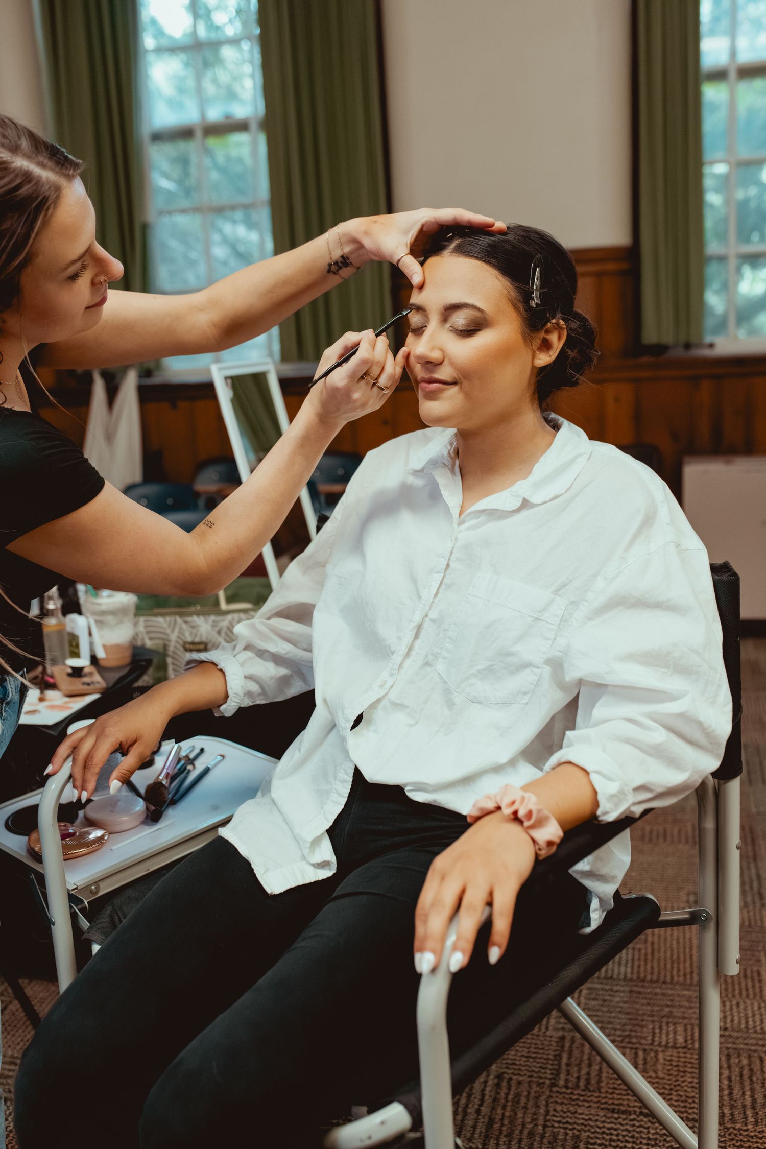 Makeup artist applies cosmetics to client wearing white shirt in sequence of preparation shots.