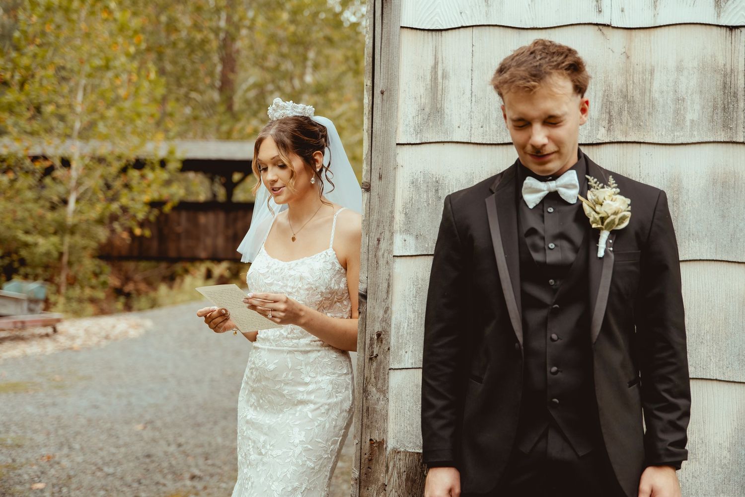 A bride and groom share intimate moments in front of a rustic barn wall during their wedding photoshoot.