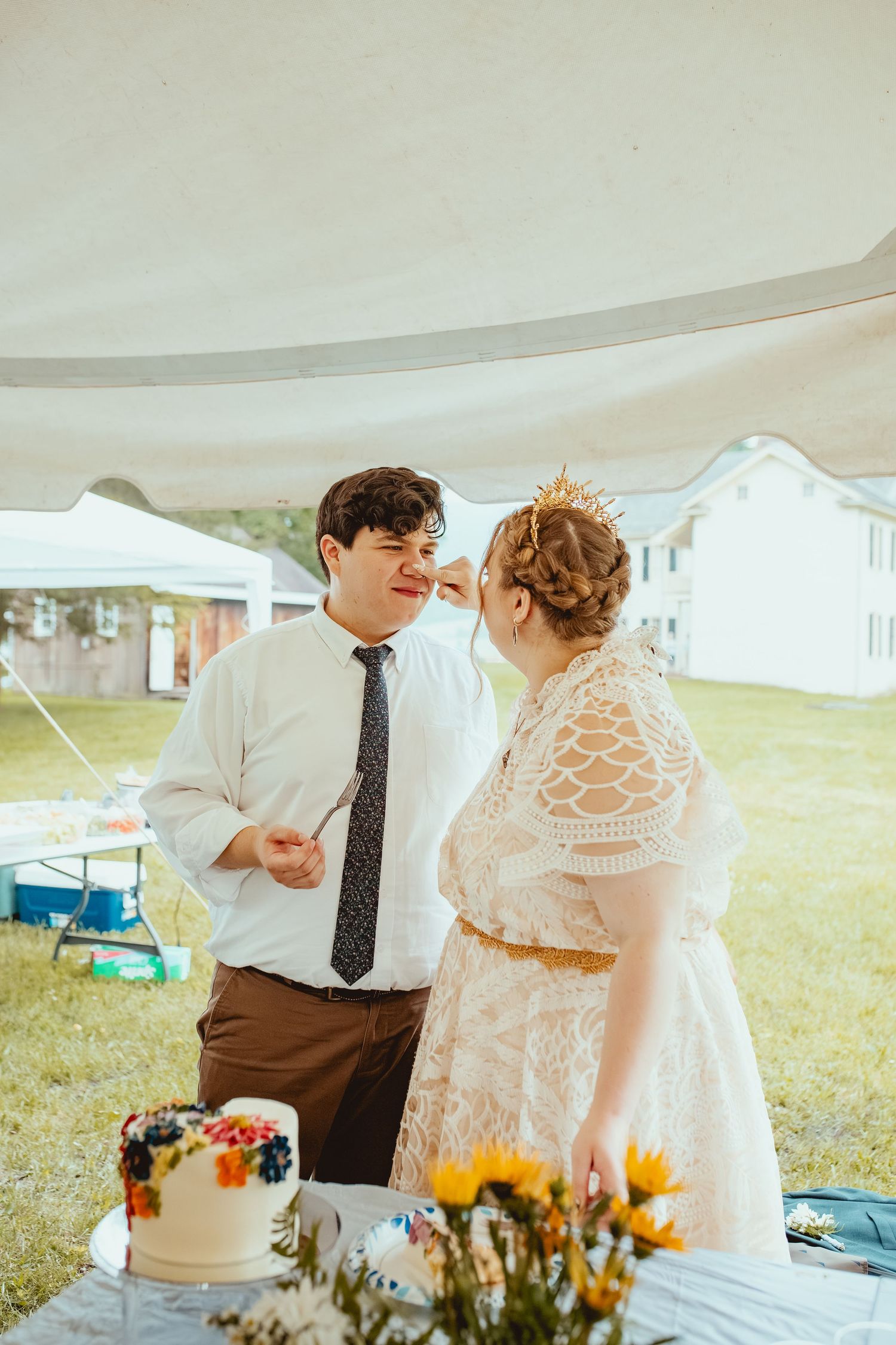 A wedding couple shares tender moments under a white tent with autumn floral decorations.