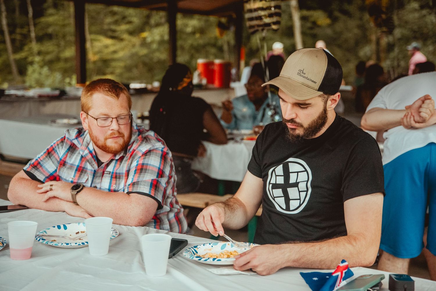 People enjoying a casual meal together at a long table with plates of food and drinks.