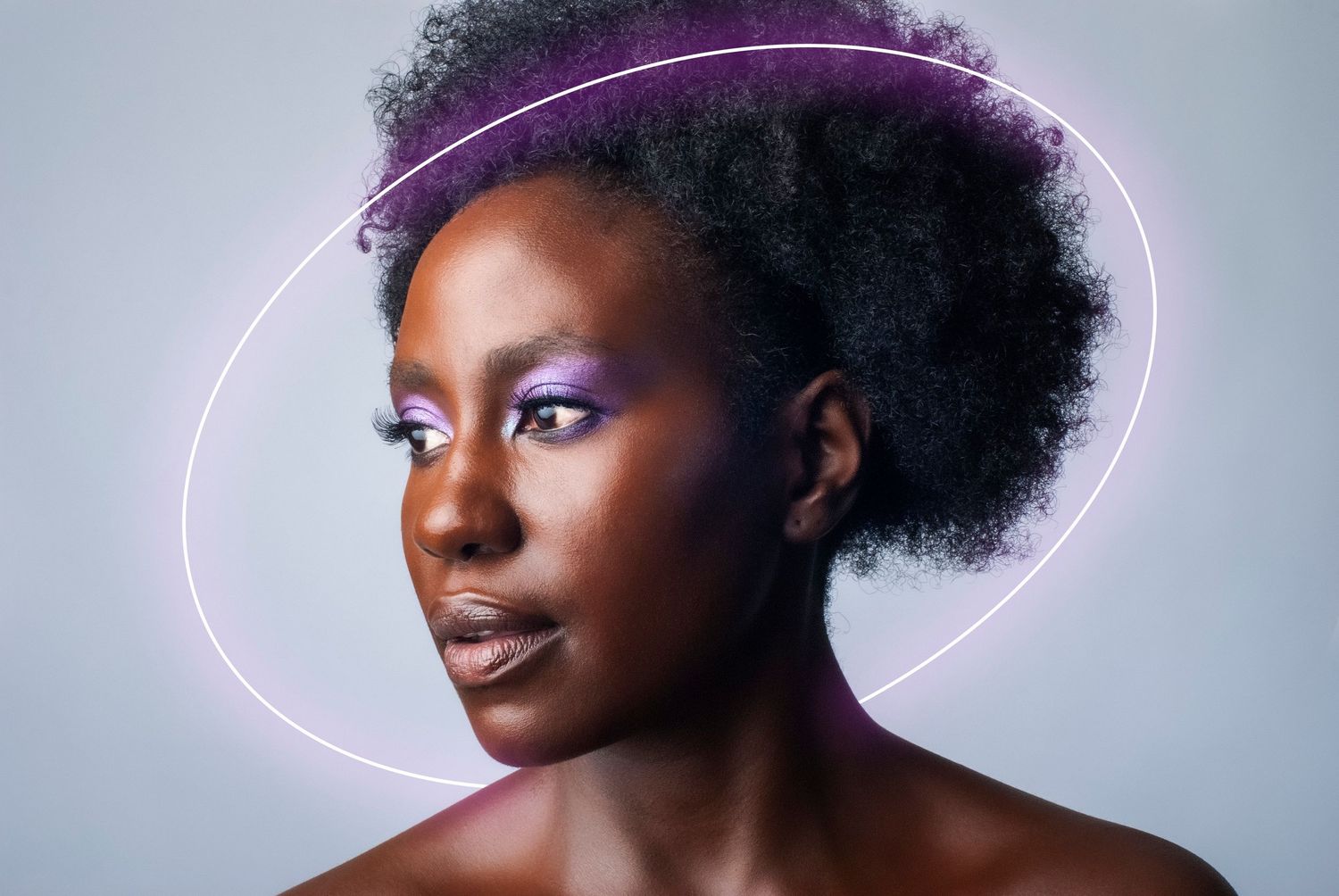 Beauty portrait with neon purple halo light effect against gray background.
