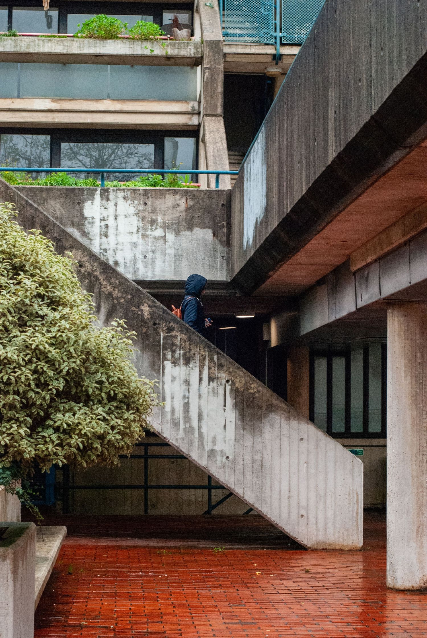 Modern brutalist architecture featuring diagonal stairs and red brick flooring.