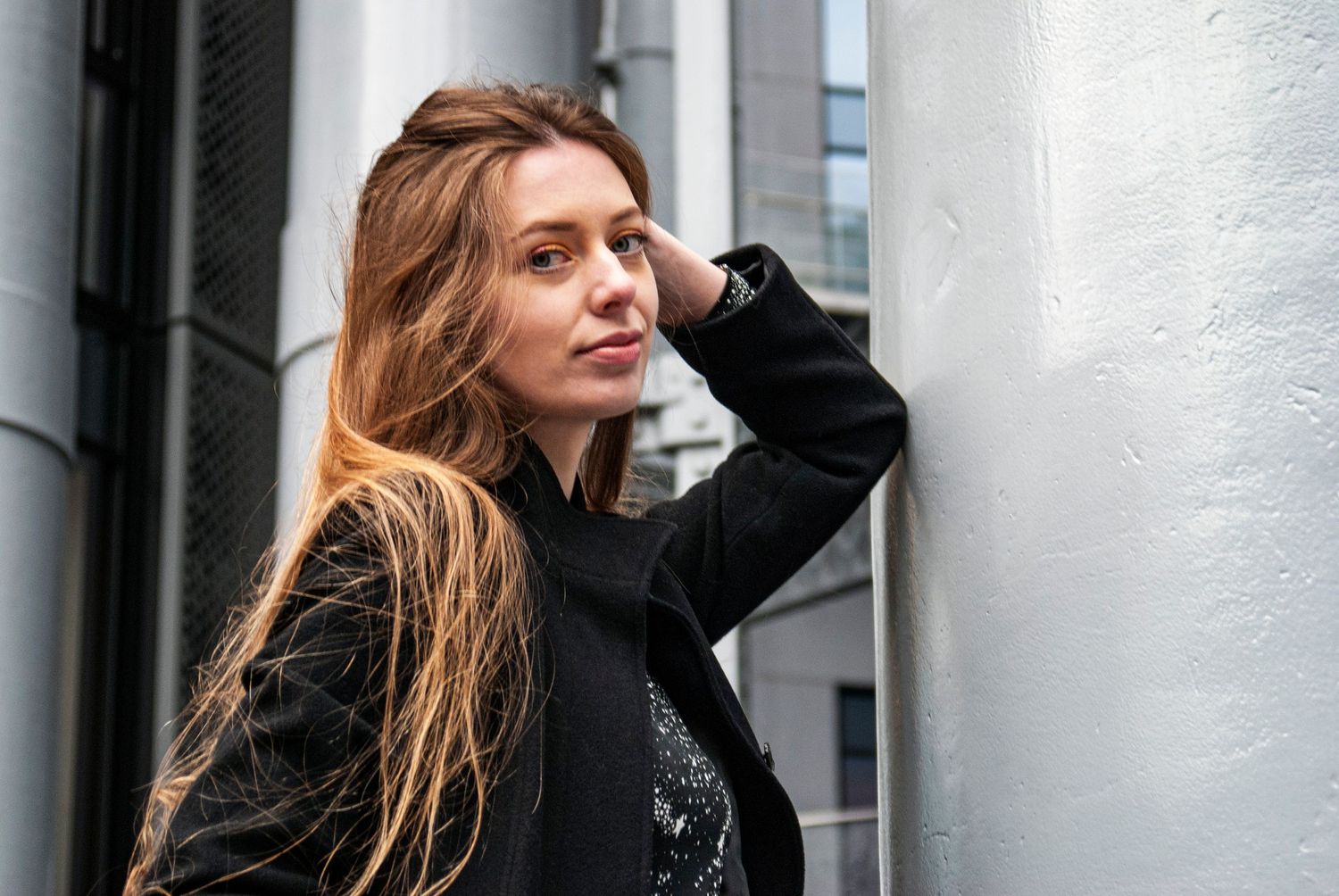 Portrait against modern building exterior with dramatic lighting and architectural details.