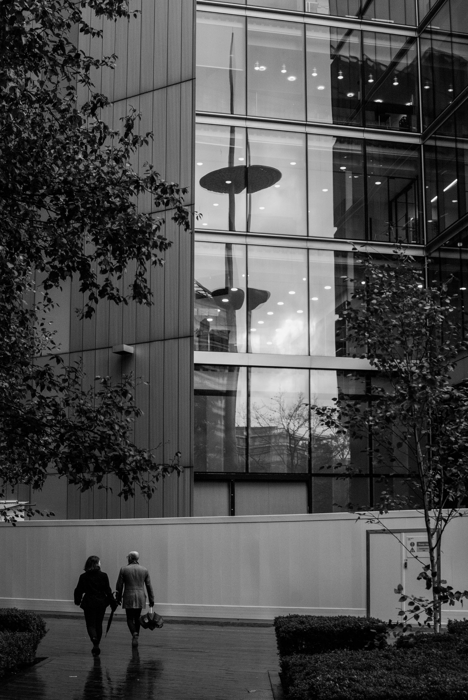 Black and white image of office building exterior with modern lighting fixtures and trees.