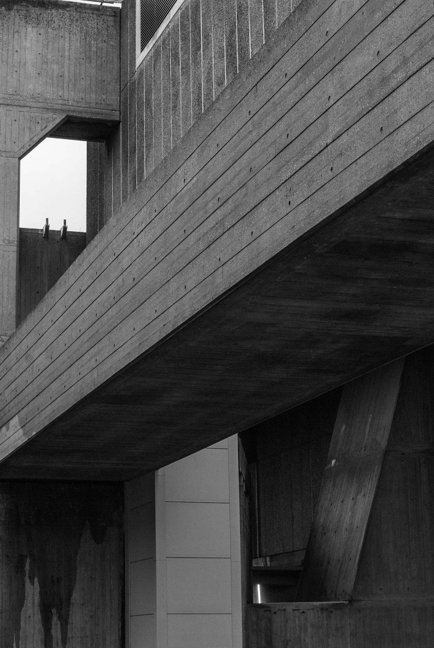 Geometric wooden staircase detail with angular lines and shadows in brutalist architectural style.