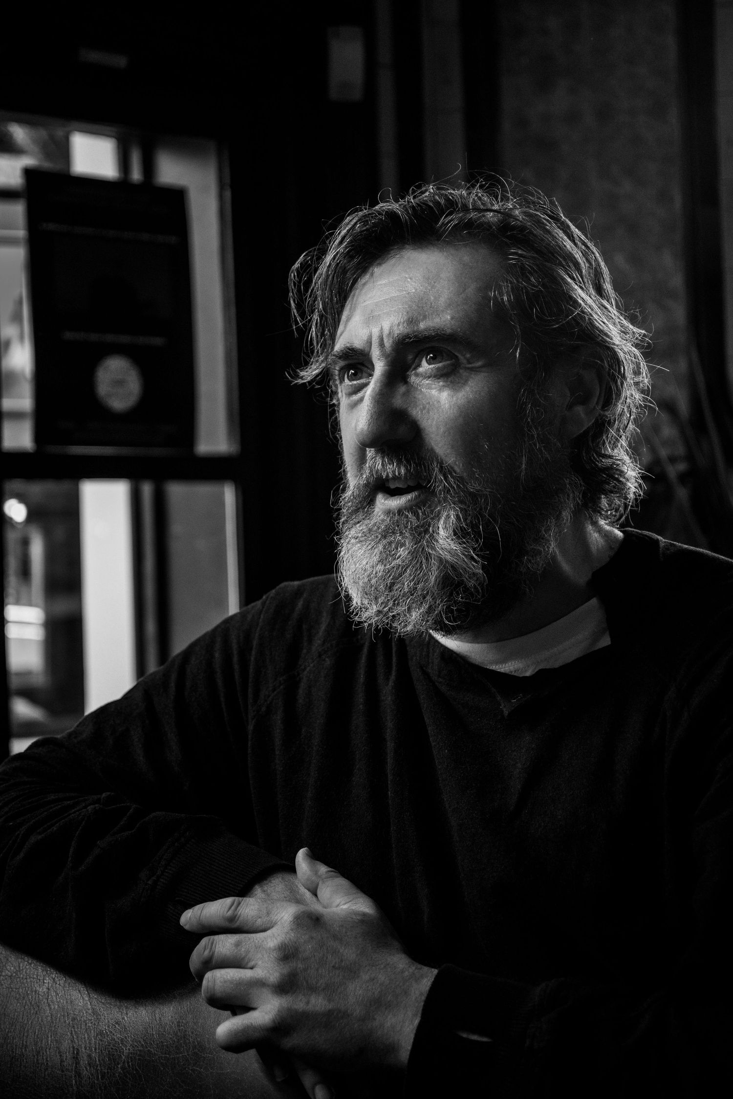 Dramatic black and white portrait of bearded man in dark lighting.
