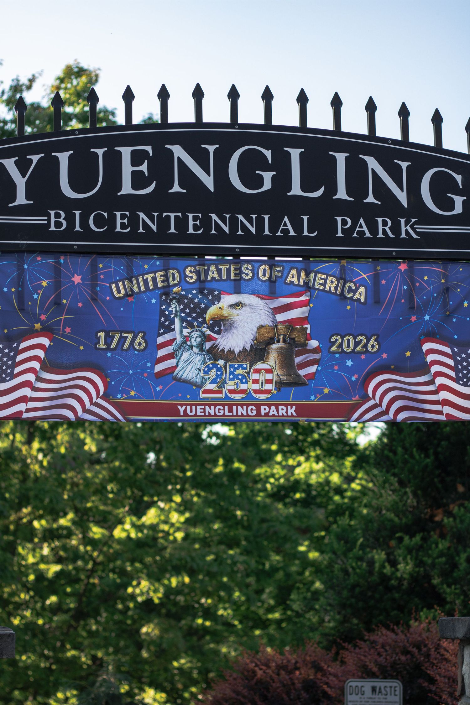 Yuengling Bicentennial Park sign with patriotic USA 1776-2026 banner featuring bald eagle and American flags.