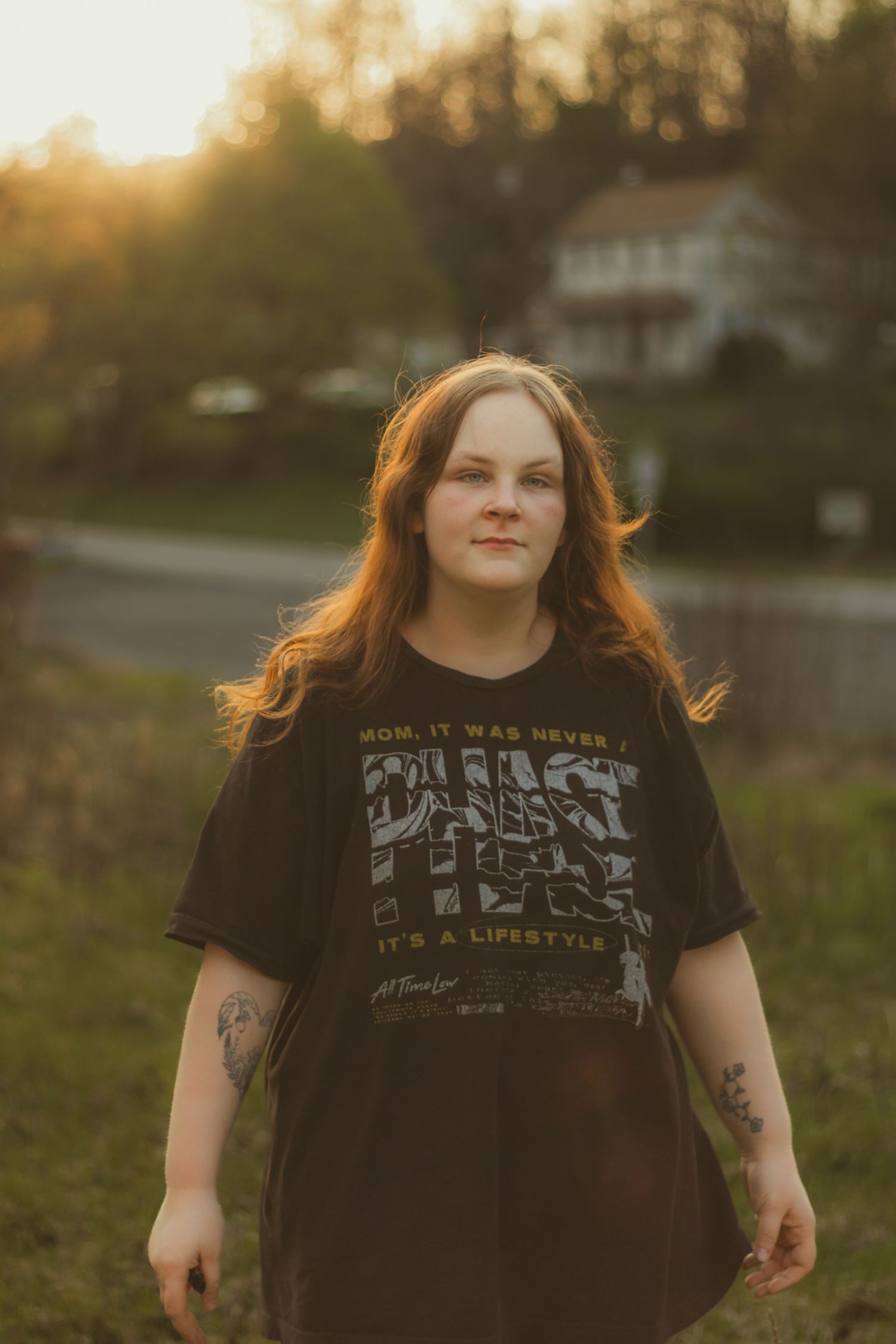 Young woman with long auburn hair walks toward camera at golden hour wearing an oversized black Phish lifestyle graphic tee.