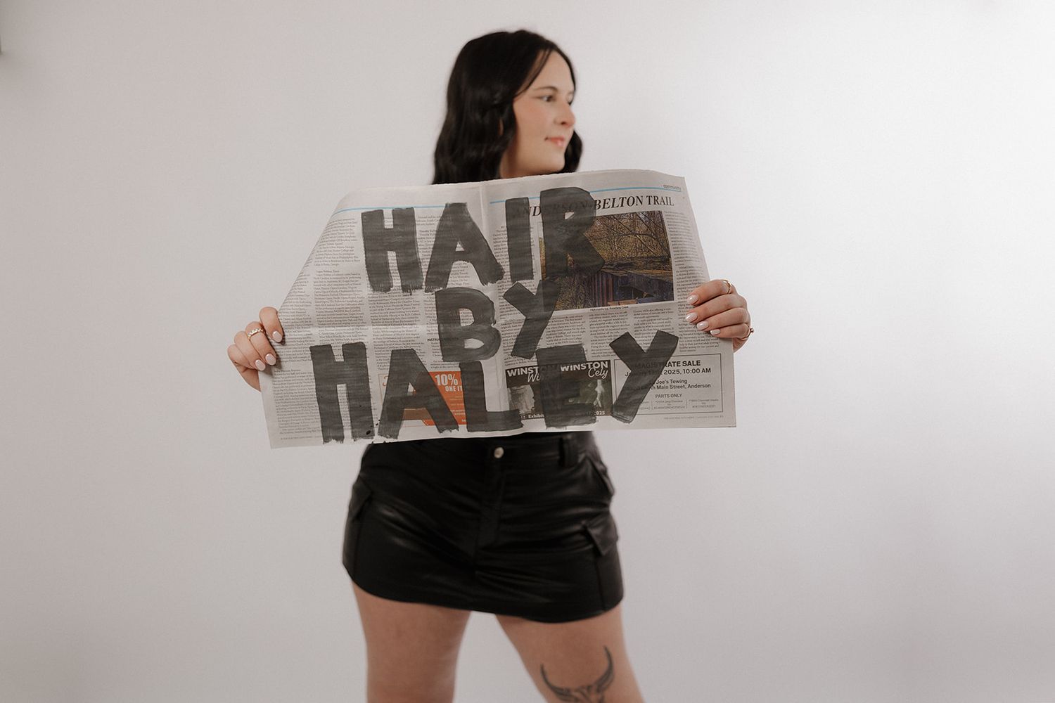 A person in black shorts holds up a handmade cardboard sign with text against a white background.
