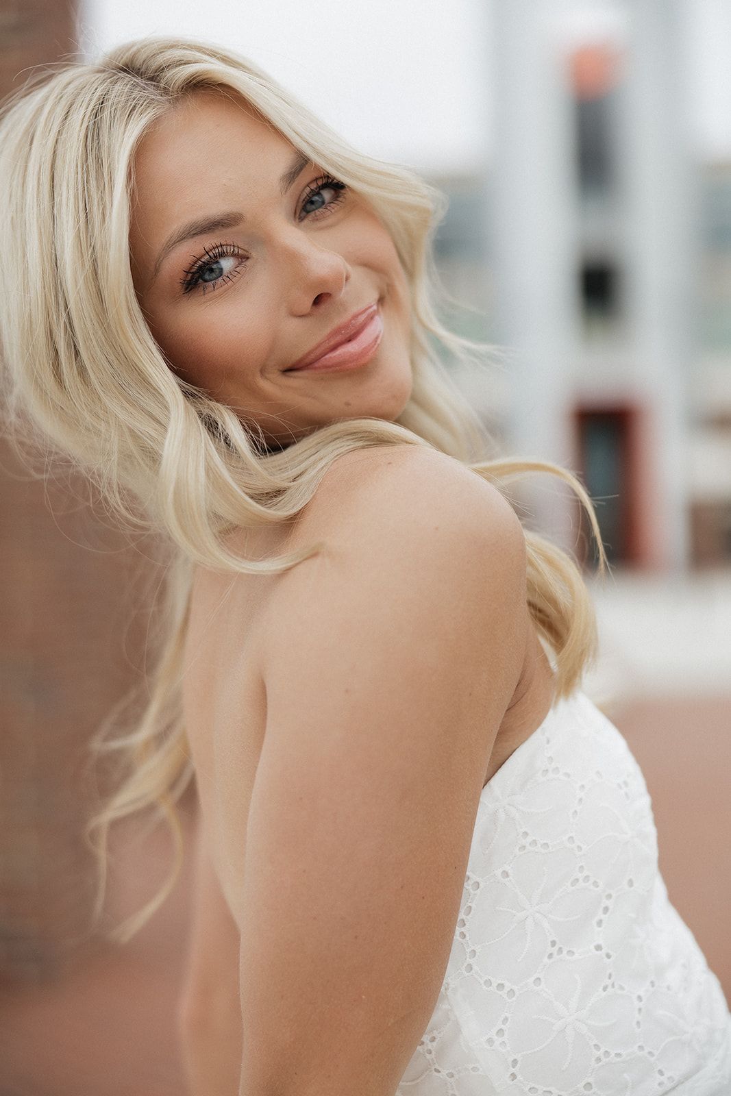 Portrait in white eyelet dress against soft blurred background creating romantic lifestyle mood.