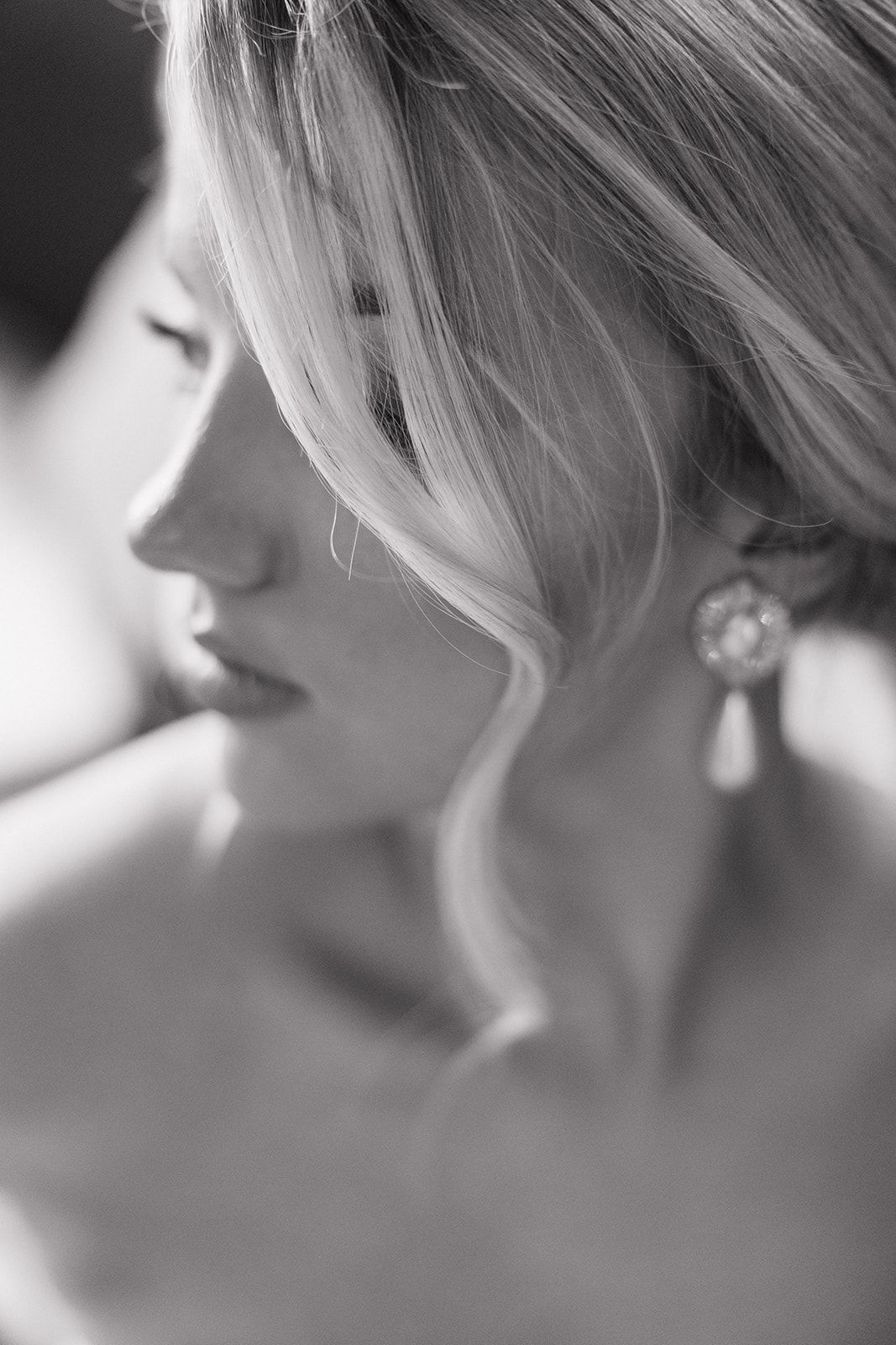 Artistic black and white close-up photo of a profile with wavy blonde hair and an elegant dangling earring.