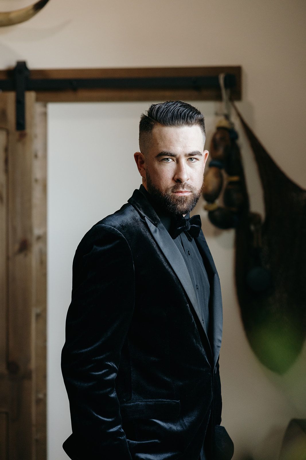 Portrait series of a groom in a black suit against a neutral indoor background.