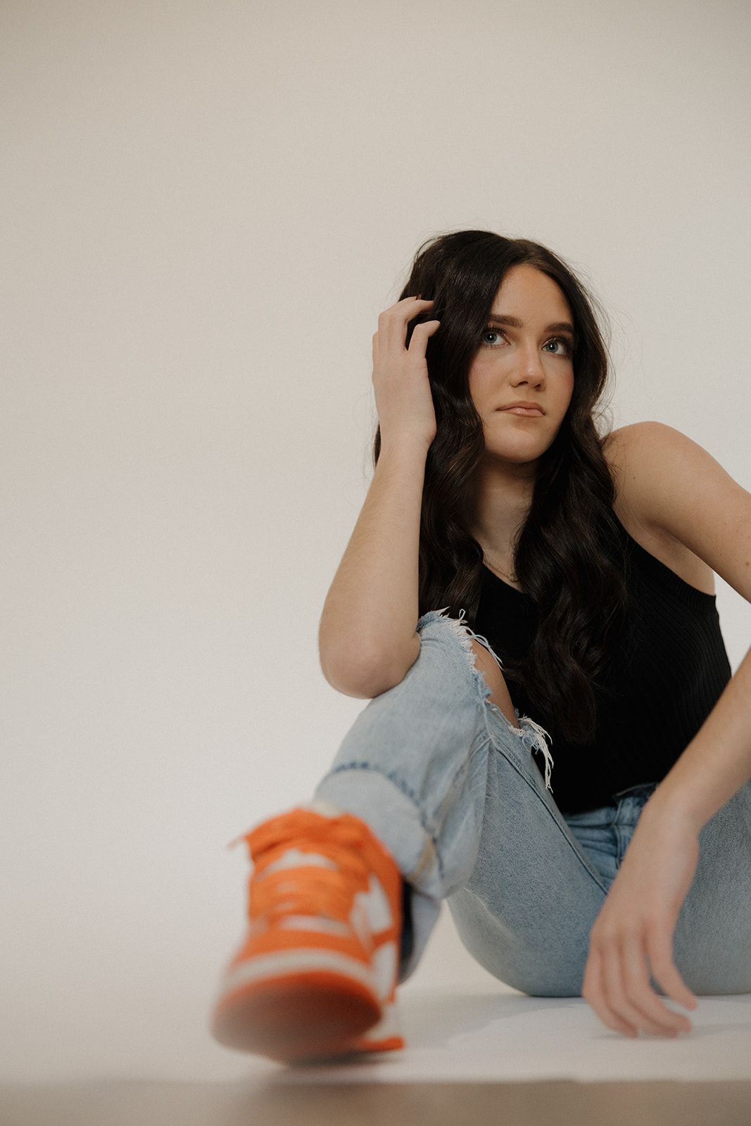 A sequence of minimalist photos shows someone in light denim and orange sneakers posing against a white background.