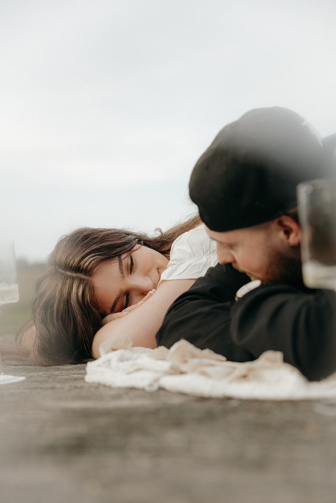 An intimate moment between a couple laying together outdoors during an engagement photoshoot.