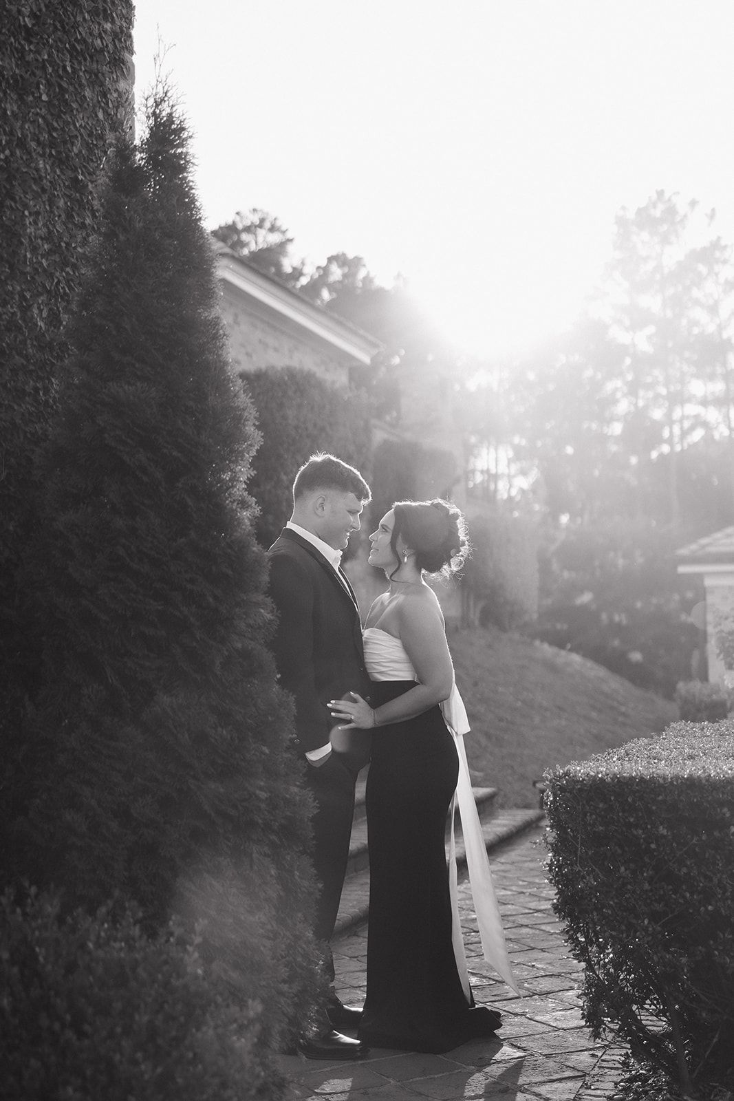 A couple embraces in formal attire during a romantic sunset photoshoot.