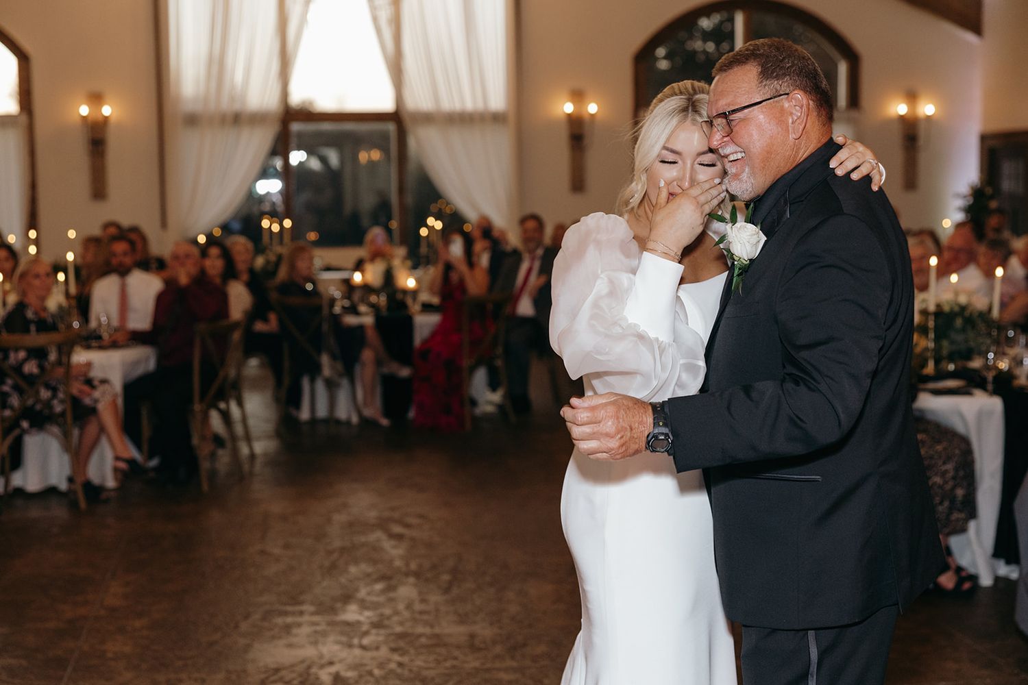 An emotional daddy-daughter dance moment, filled with tears, love, and connection—captured during a warm, candlelit wedding reception.