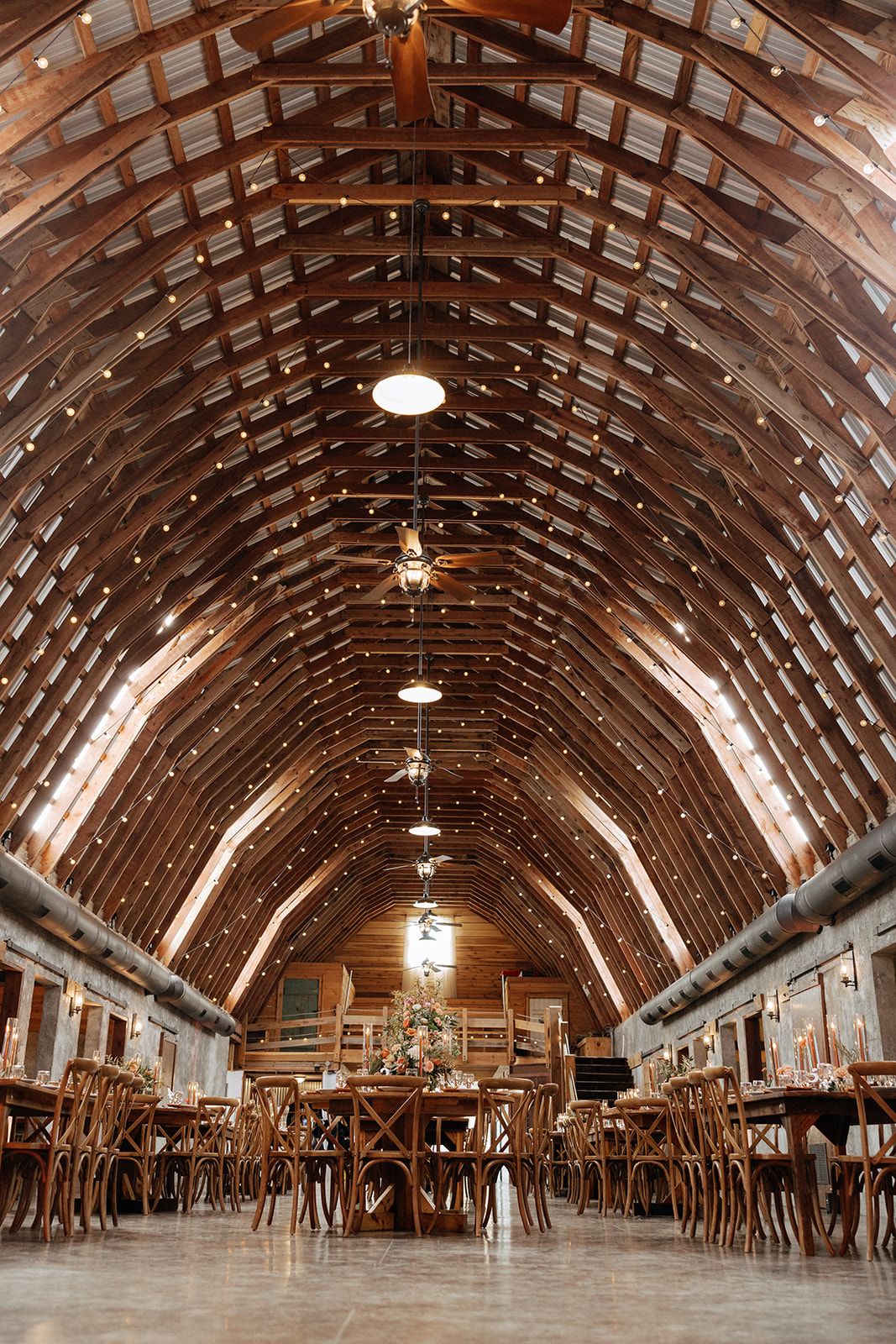 Panoramic sequence showing the interior of a massive wooden barn with arched ceiling beams and hanging lights.