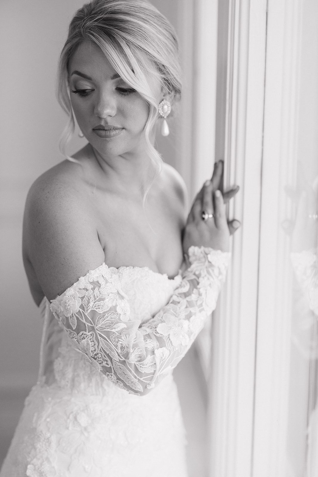 Elegant off-shoulder wedding dress with delicate lace details captured in a bright window light setting.