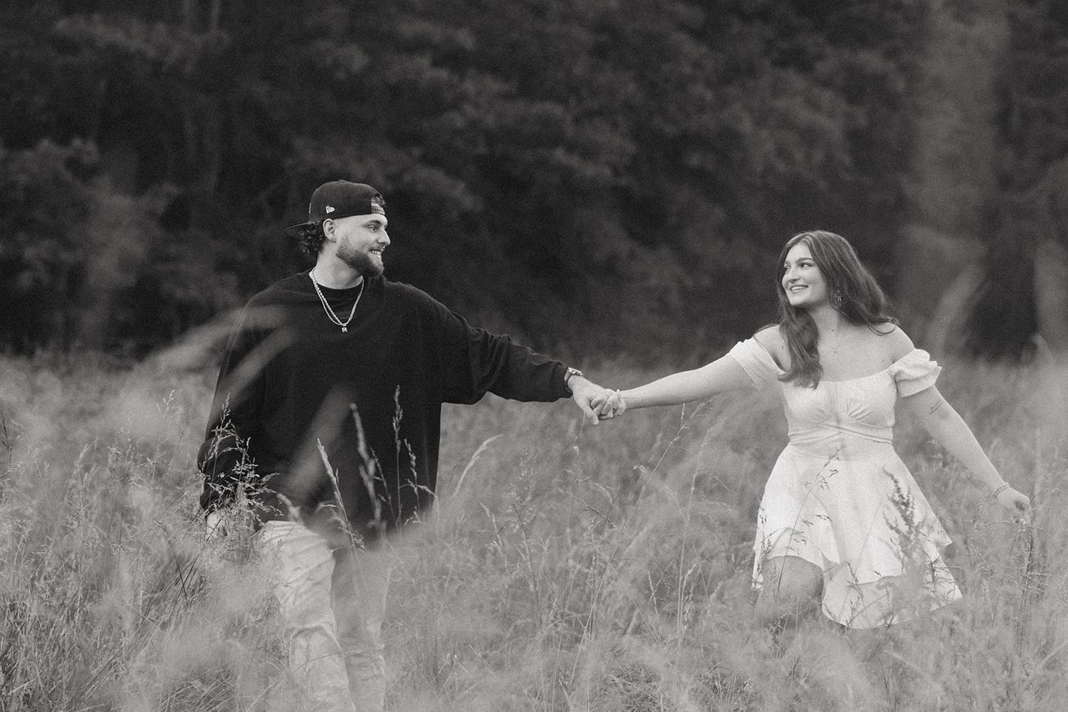 A couple in contrasting black and white outfits dances playfully in a misty meadow.