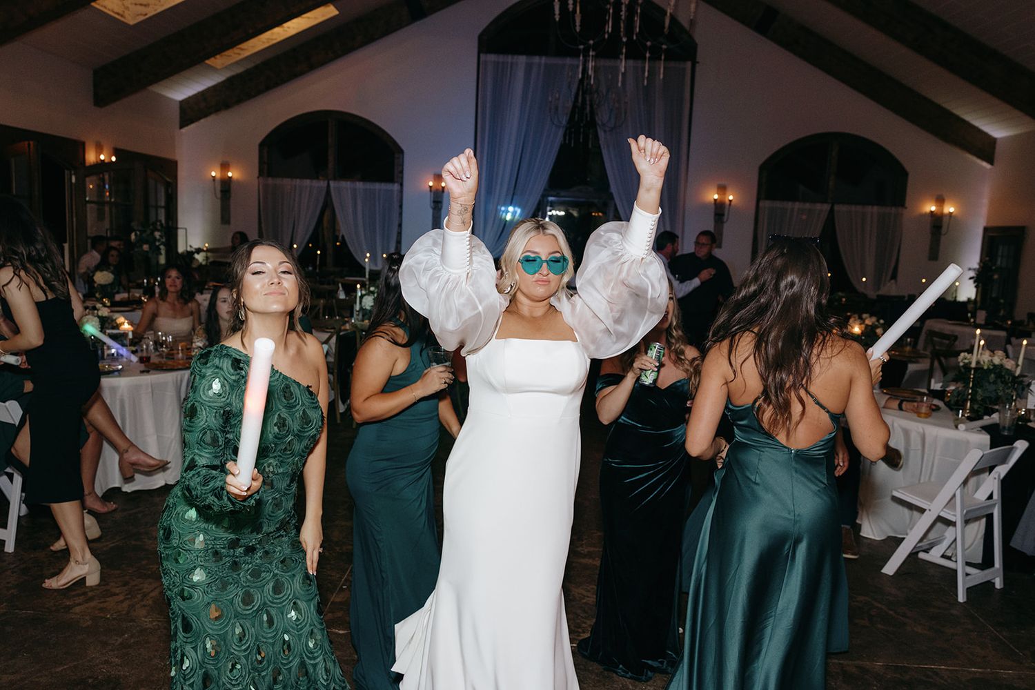 Reception celebration with dancers in dark green dresses on the dance floor.