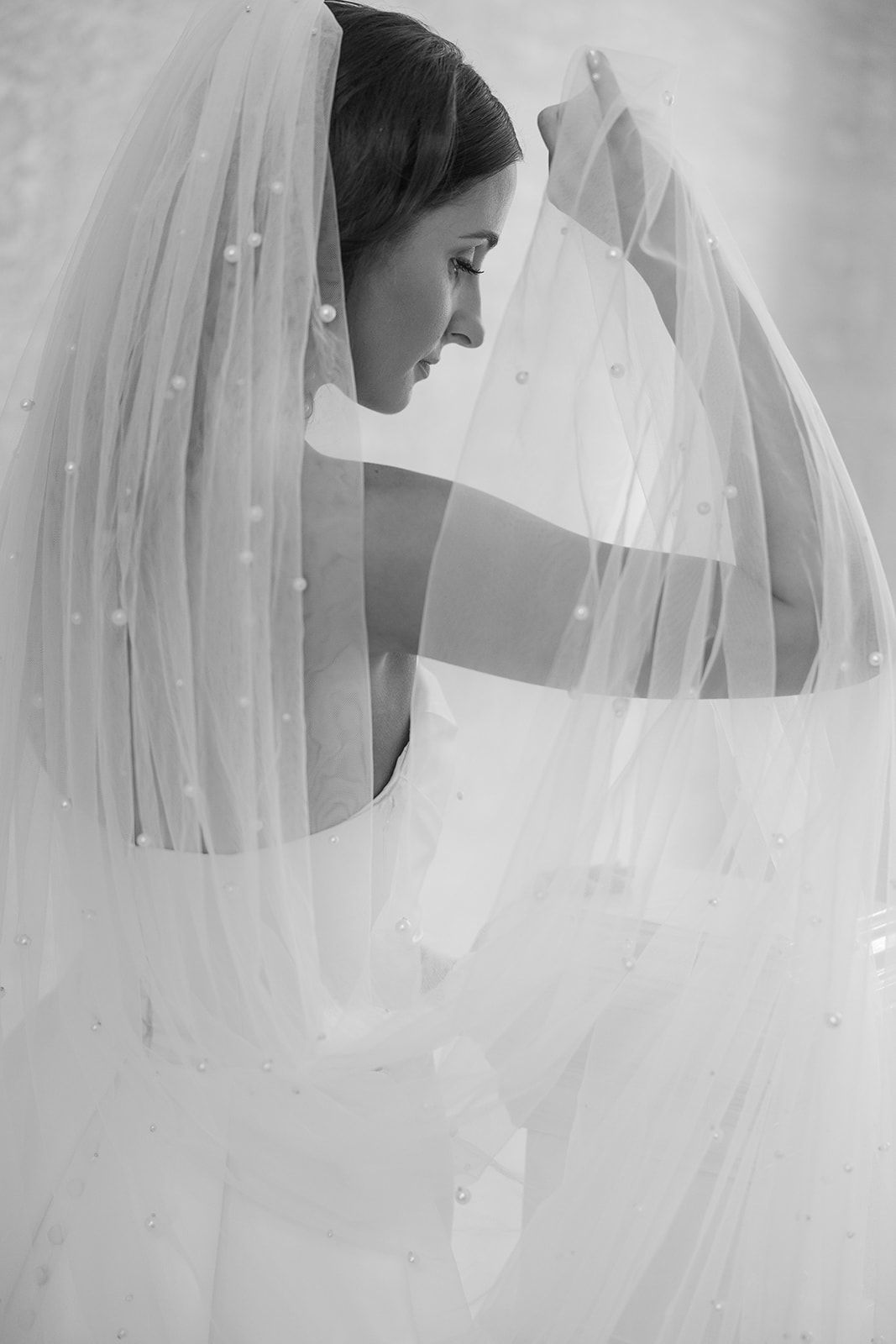 Ethereal black and white portrait showing delicate details of a wedding veil.