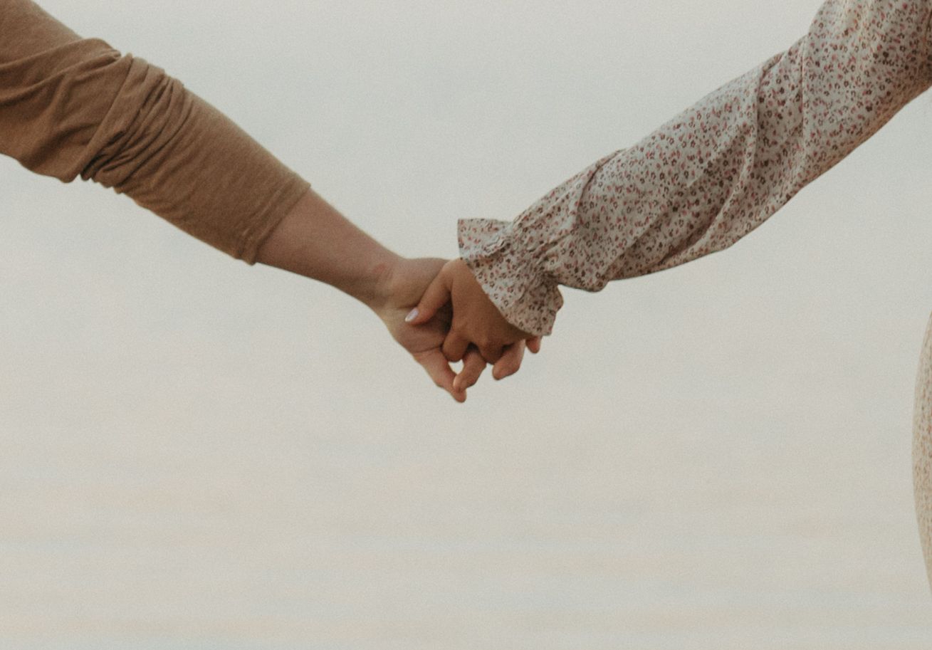 Close-up of couple holding hands against neutral background showing connection and intimacy.