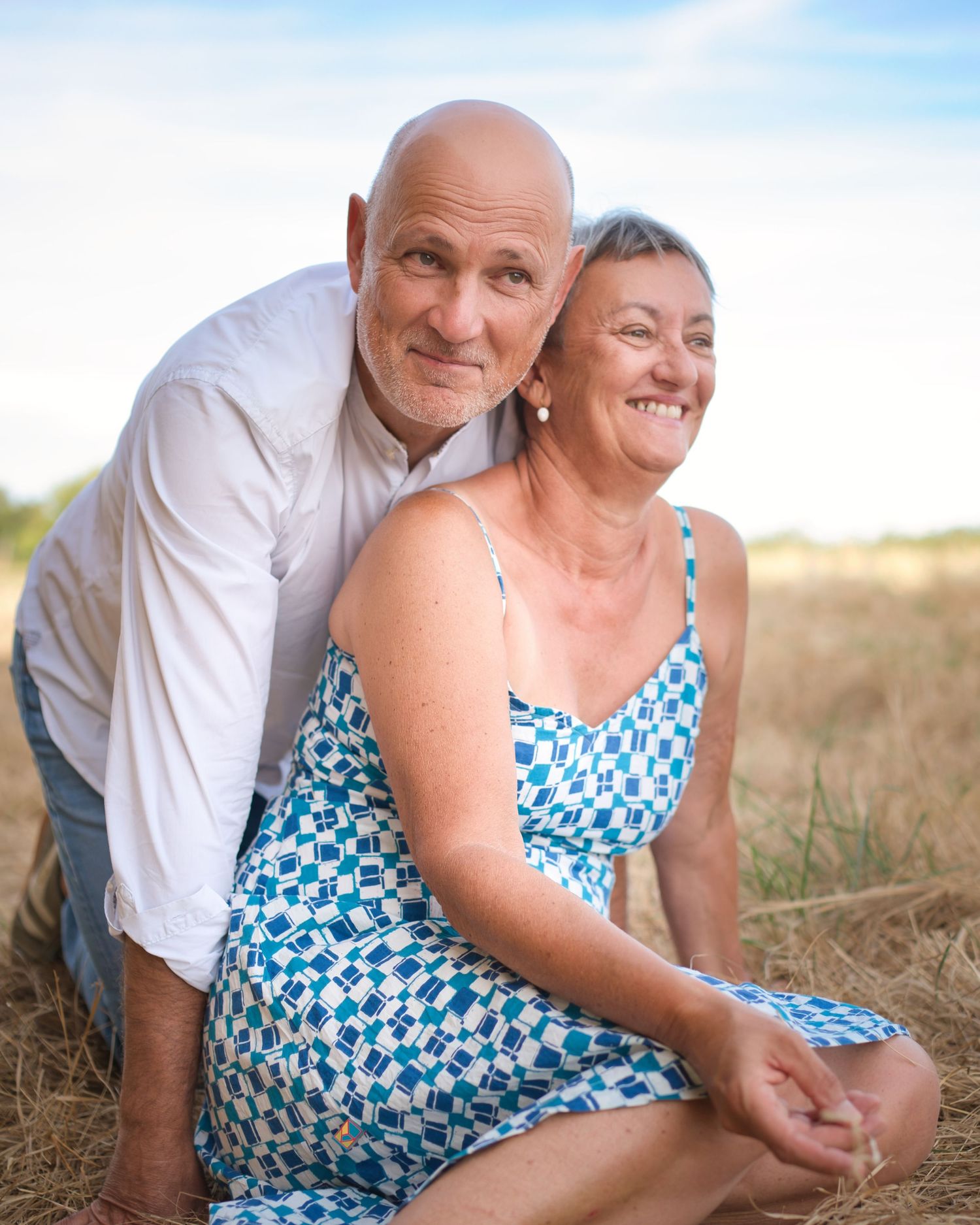 Playful couple's portrait session in natural setting with golden grass.