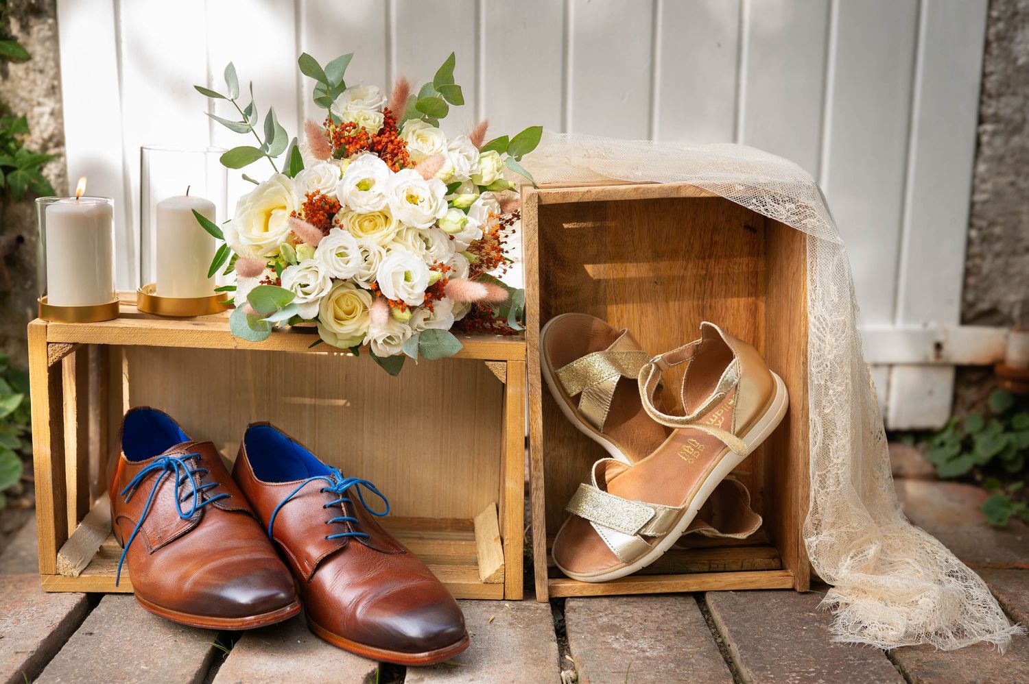 Brown leather wedding shoes displayed with wooden crates and floral arrangements.