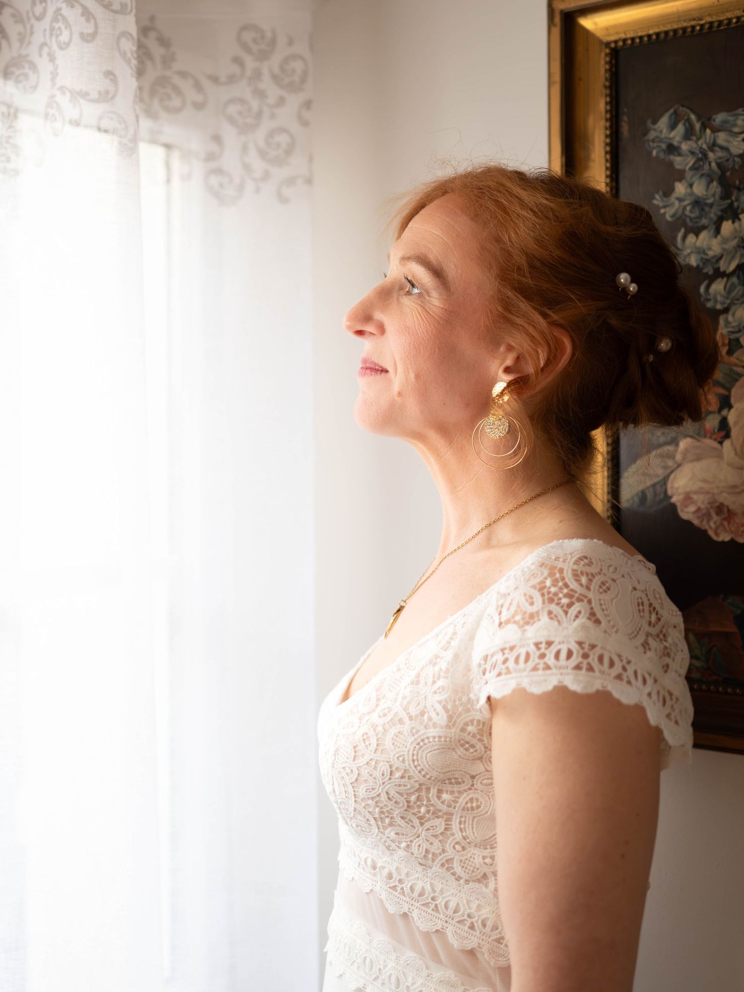 Side profile in natural window light wearing lace cap sleeve wedding dress.