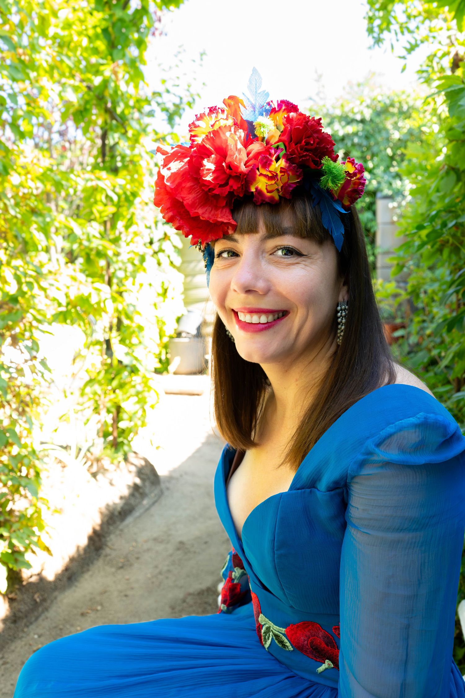 Detailed shots of bright red floral crown and blue dress against garden backdrop.