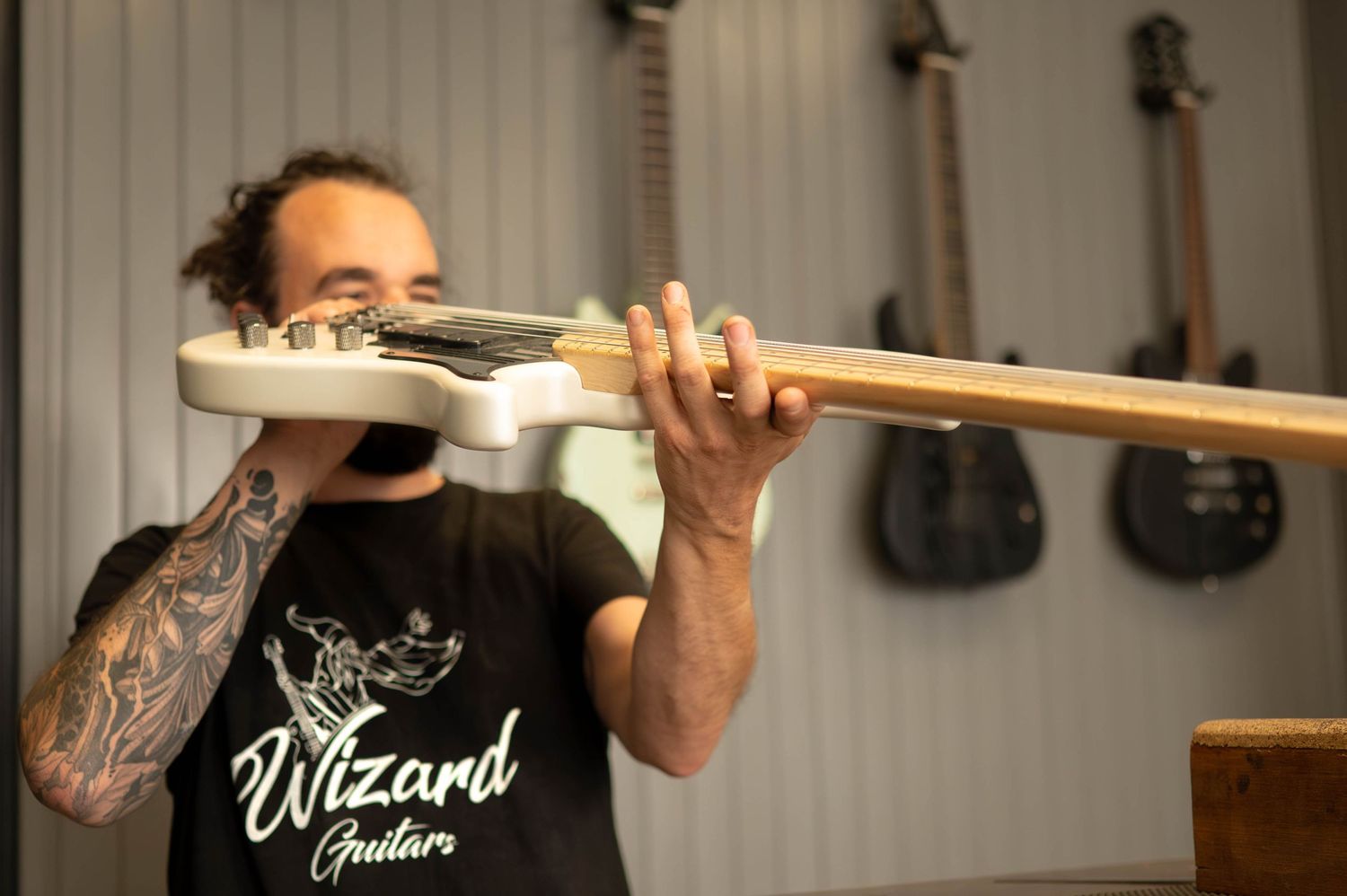 Skilled craftsman working on custom guitar modifications in a professional workshop interior.