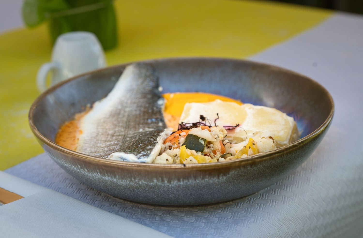 A series of elegant plated dishes in gray ceramic bowls showcasing modern fine dining presentation.