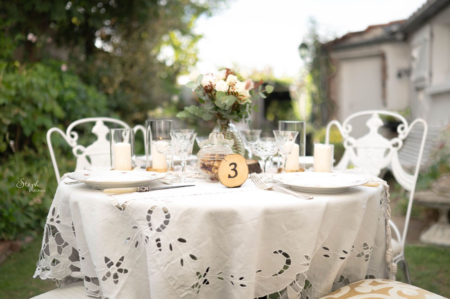 Elegant outdoor table settings with white linens and floral centerpieces arranged for an upscale garden party.