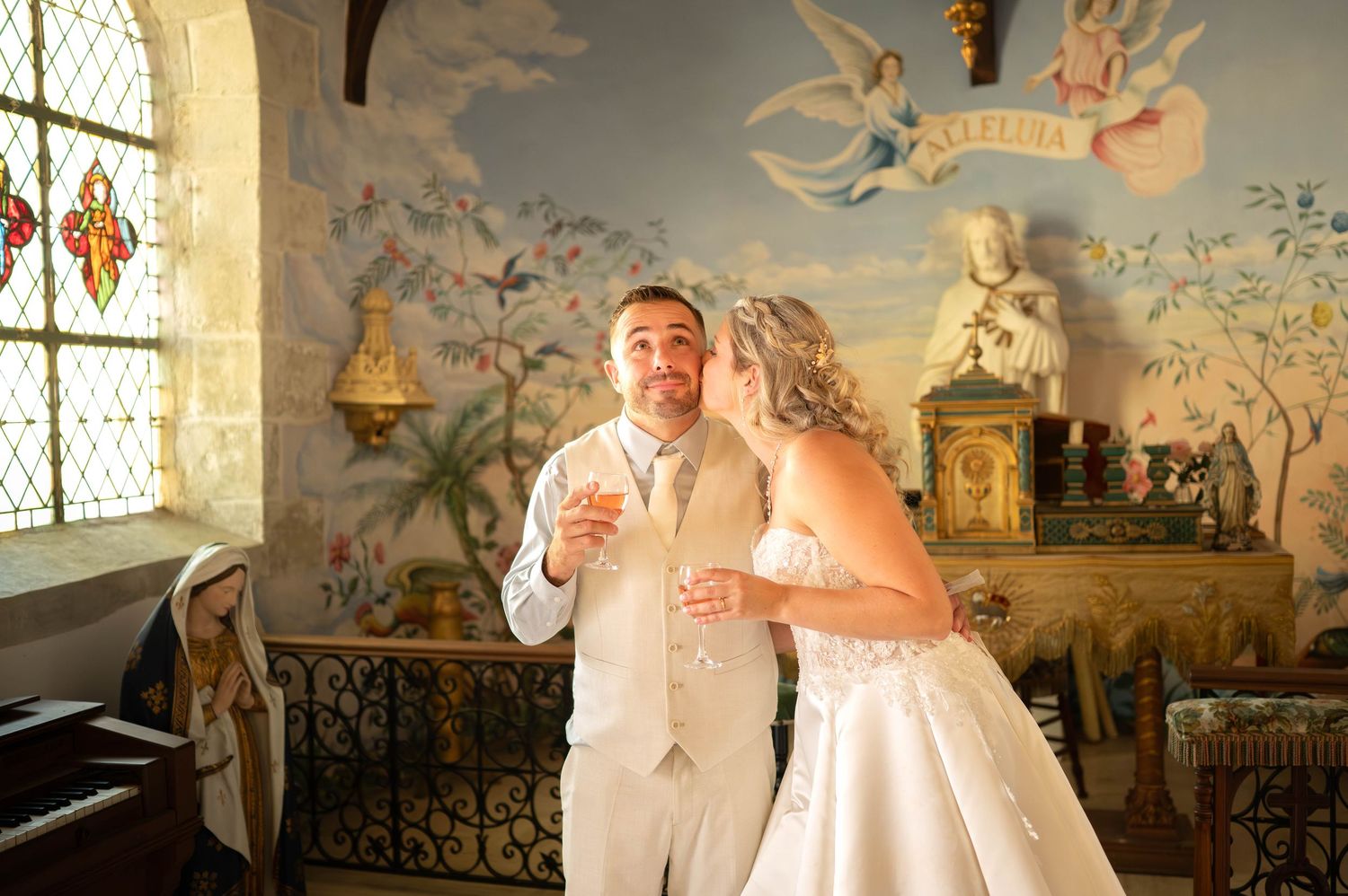 Wedding couple poses in an elegant room with ornate wall murals featuring cherubs and decorative artwork.